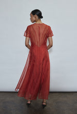 Model wearing the voluminous Kamperett Anemoia Midi dress in Rust silk organza, highlighting the architectural French seams and graceful midi-length silhouette.