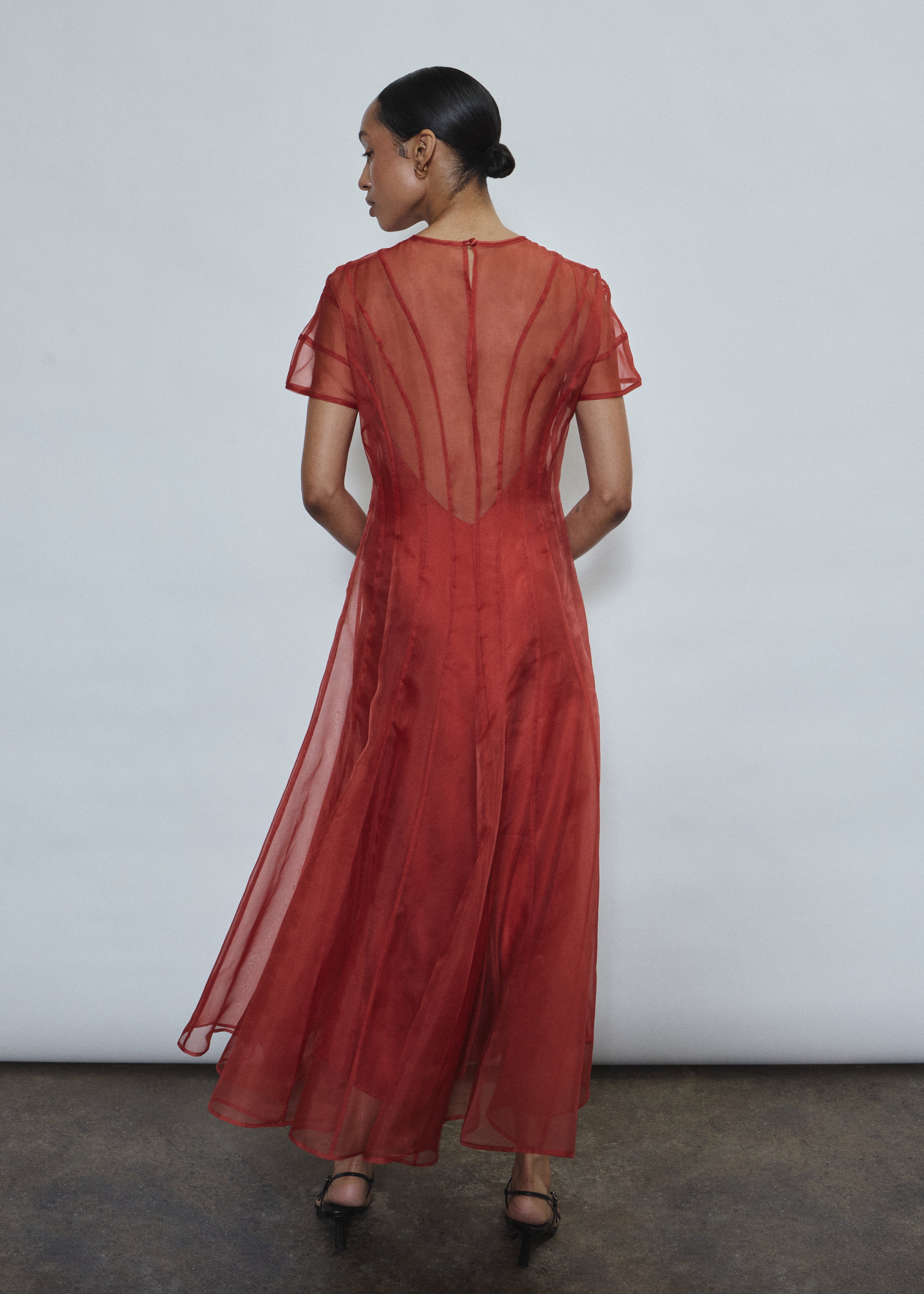 Model wearing the voluminous Kamperett Anemoia Midi dress in Rust silk organza, highlighting the architectural French seams and graceful midi-length silhouette.