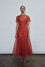 Model wearing the voluminous Kamperett Anemoia Midi dress in Rust silk organza, highlighting the architectural French seams and graceful midi-length silhouette.