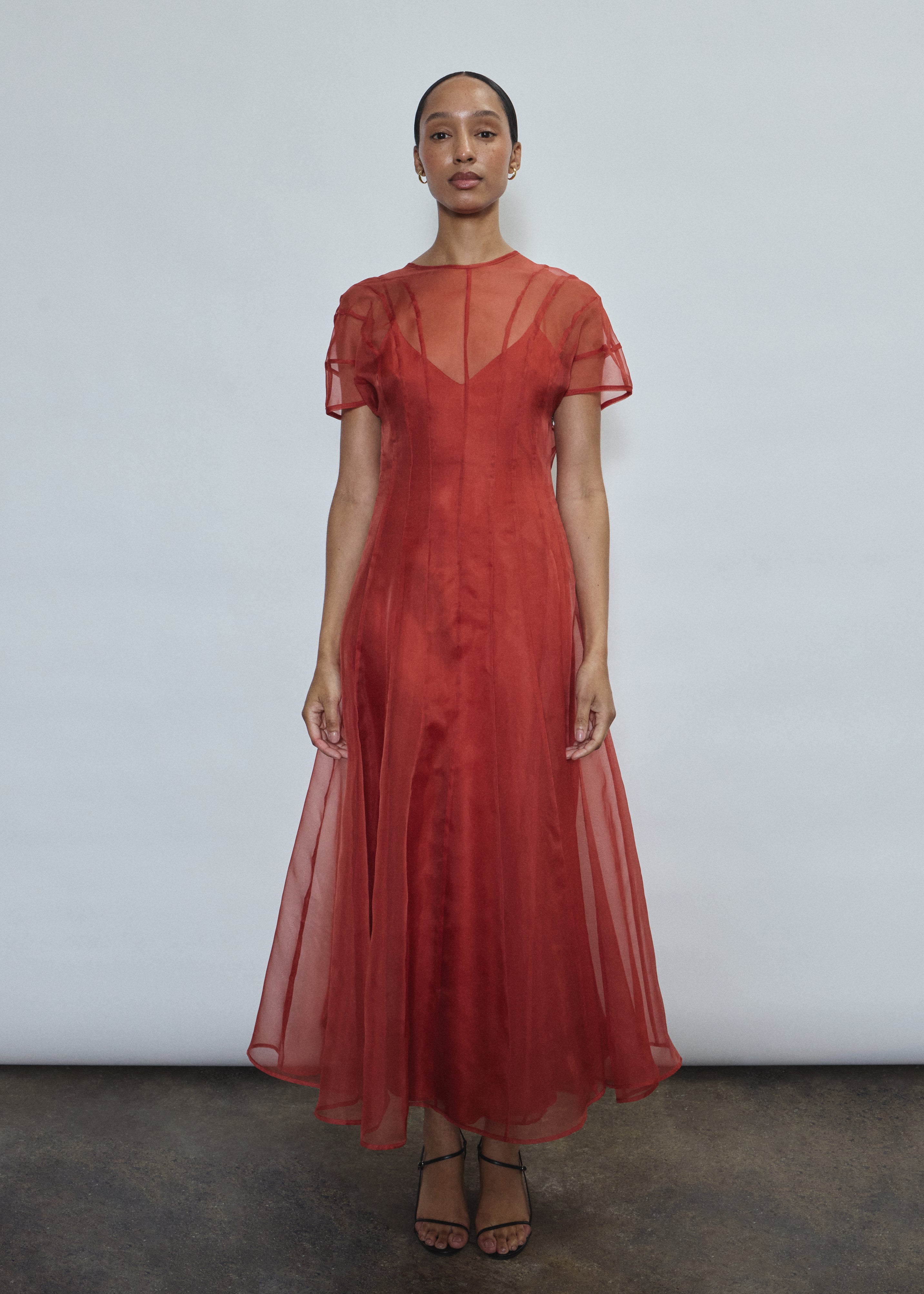 Model wearing the voluminous Kamperett Anemoia Midi dress in Rust silk organza, highlighting the architectural French seams and graceful midi-length silhouette.