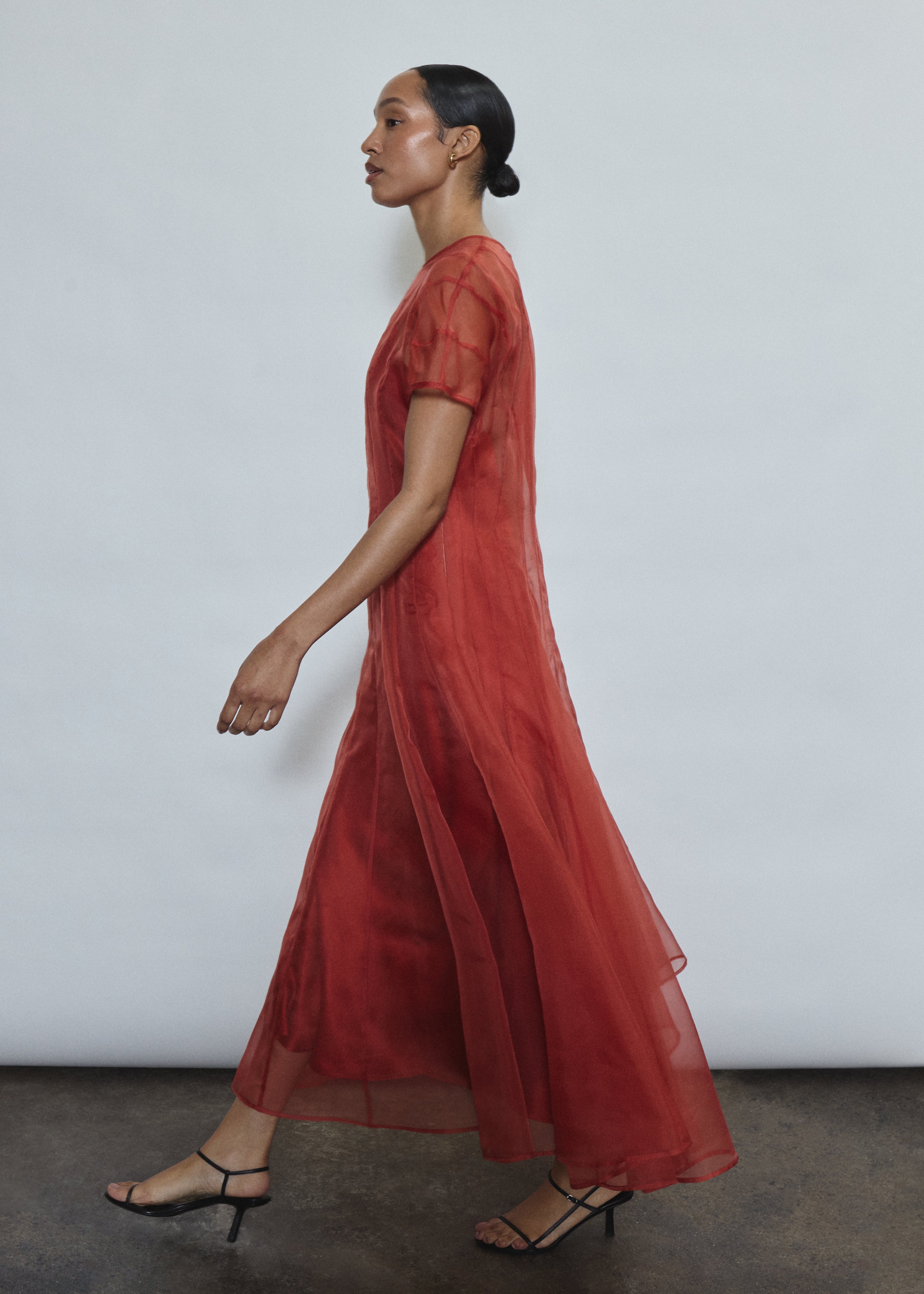Model wearing the voluminous Kamperett Anemoia Midi dress in Rust silk organza, highlighting the architectural French seams and graceful midi-length silhouette.