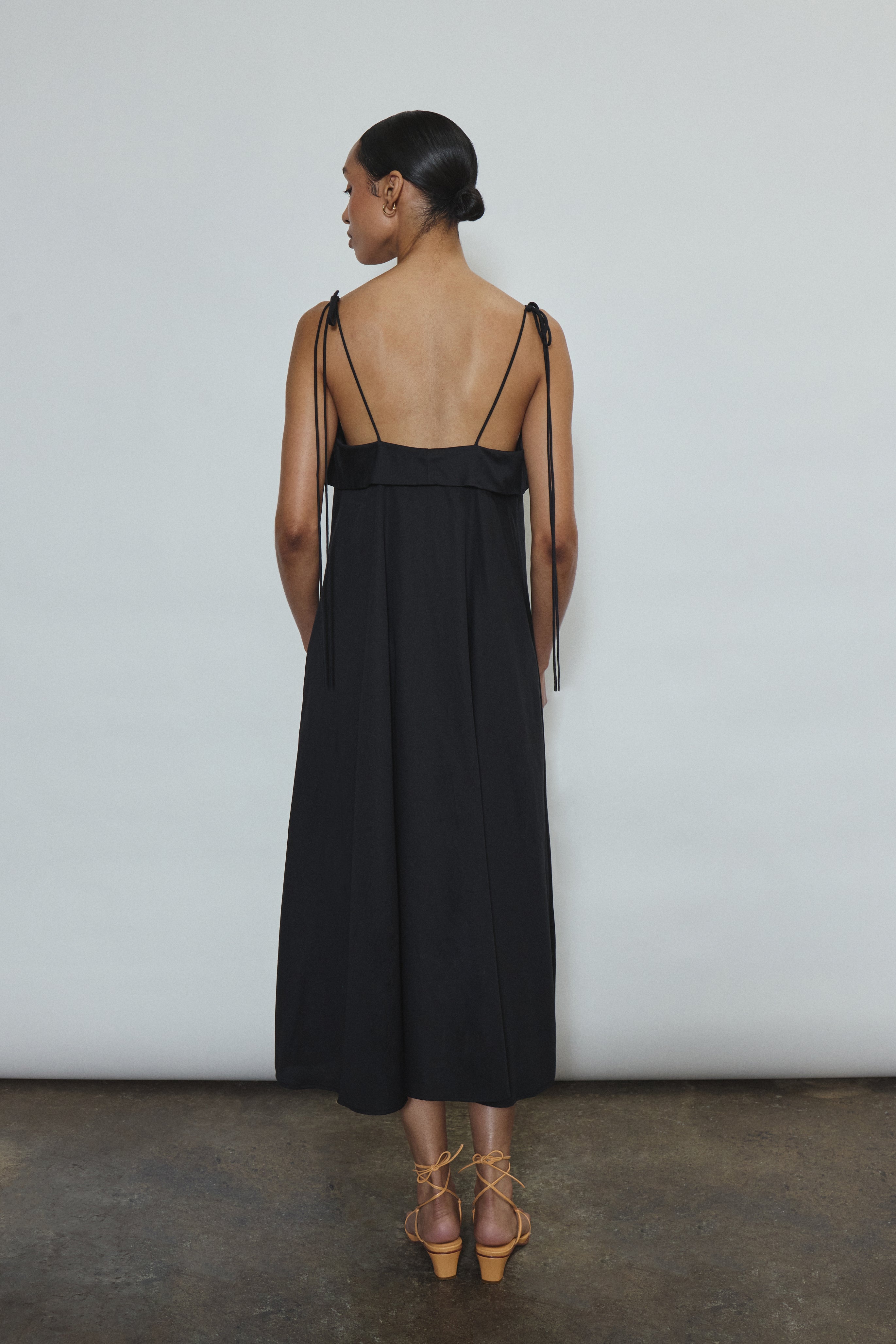 Model wearing the black Kamperett Anis Dress in black. An a-line midi dress constructed from 100% mid weight Japanese cotton. 