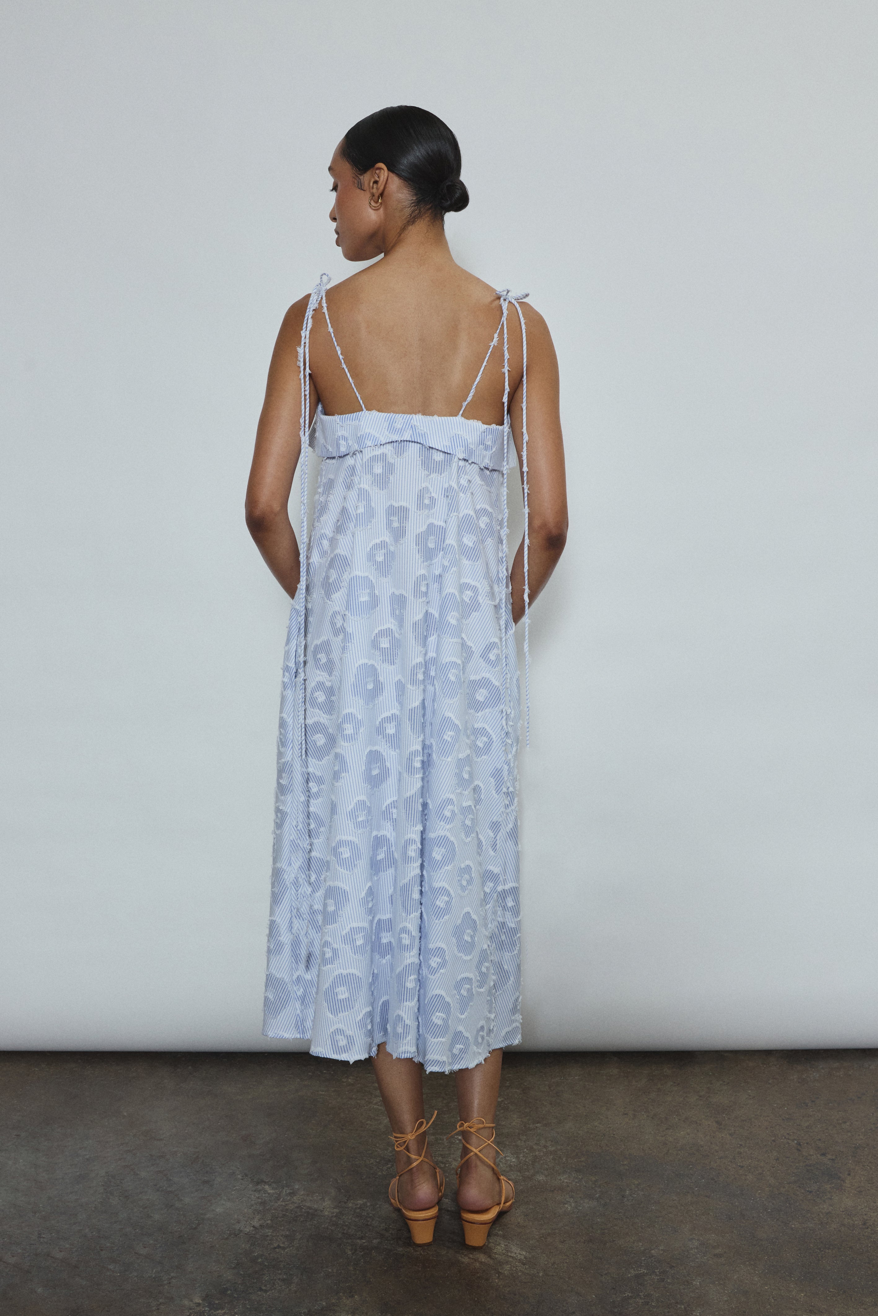 Model wearing the black Kamperett Anis Dress in blue floral. An a-line midi dress constructed from 100% mid weight Japanese cotton. 