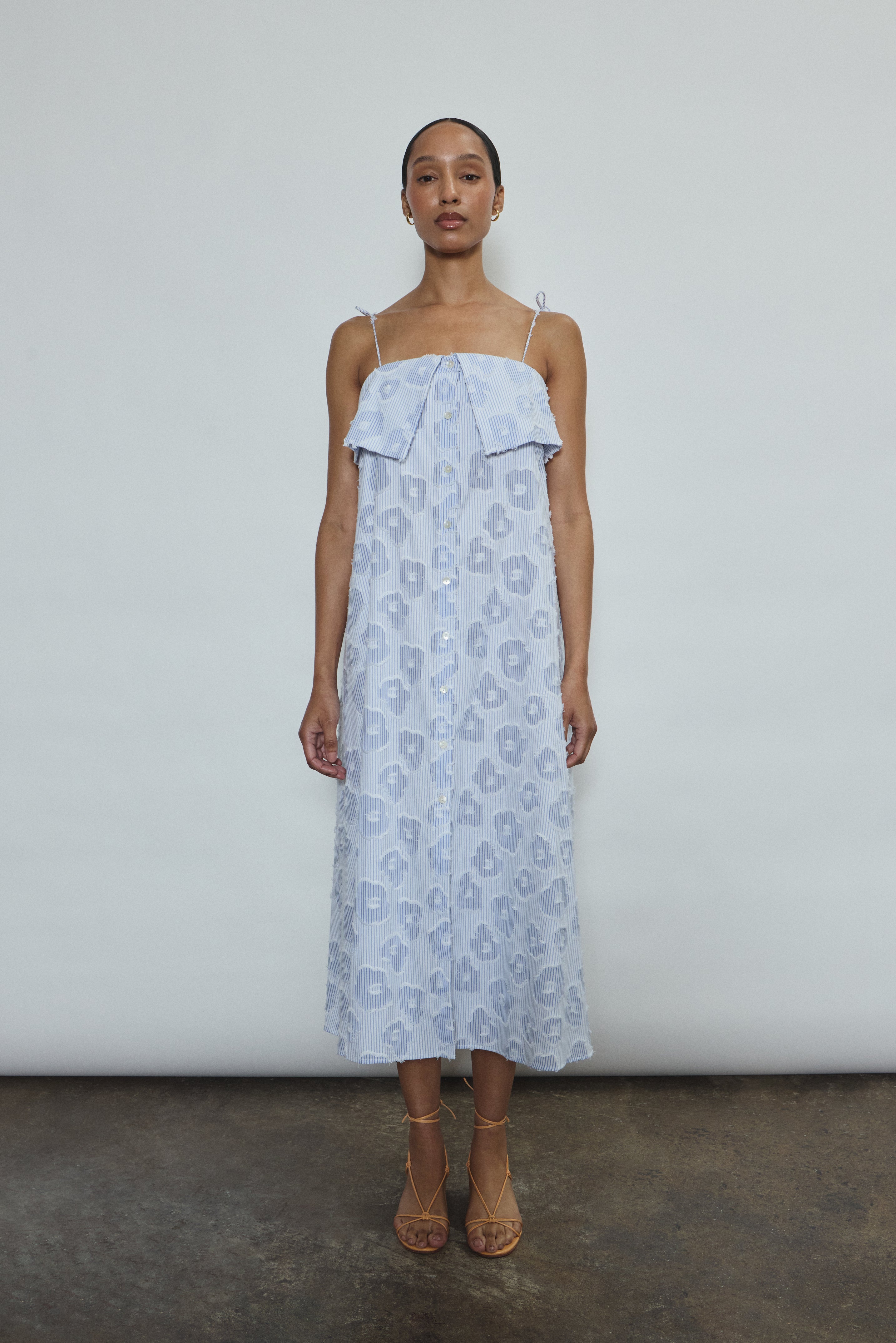 Model wearing the black Kamperett Anis Dress in blue floral. An a-line midi dress constructed from 100% mid weight Japanese cotton. 