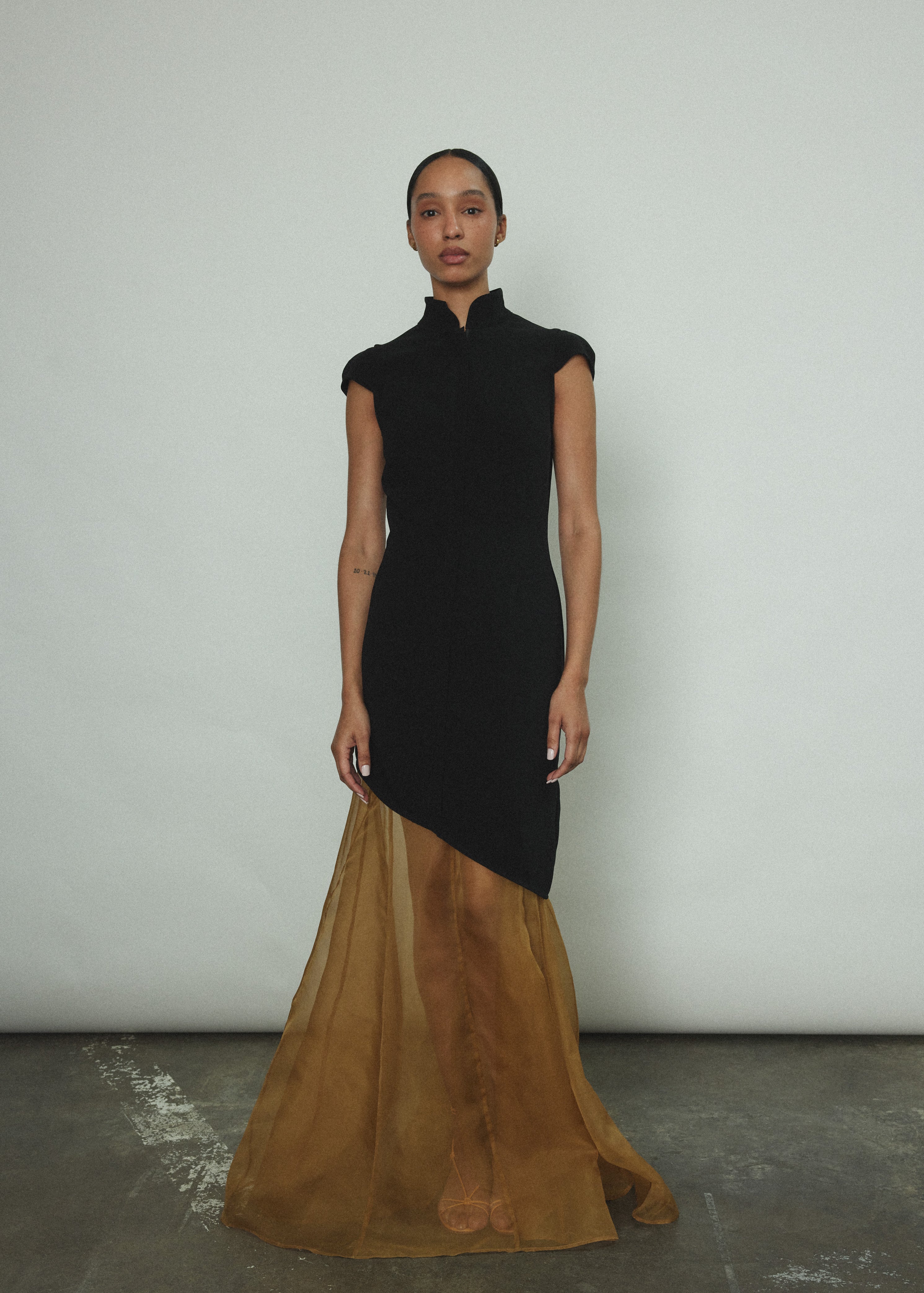 Front view of a model wearing the black wool flannel Kamperett Astrid Vest, a zip-front tunic with mandarin collar and cap sleeves.