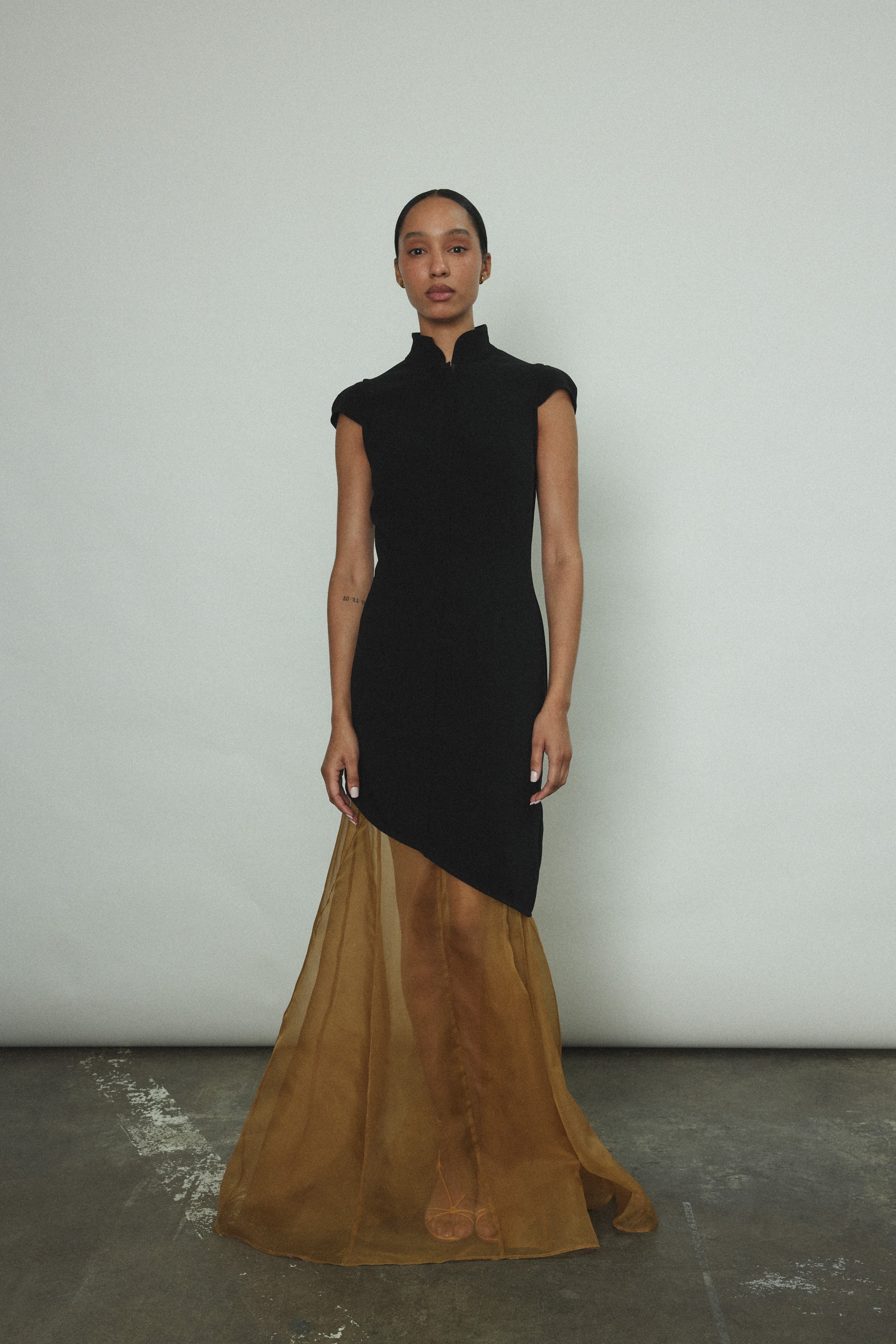 Front view of a model wearing the black wool flannel Kamperett Astrid Vest, a zip-front tunic with mandarin collar and cap sleeves.