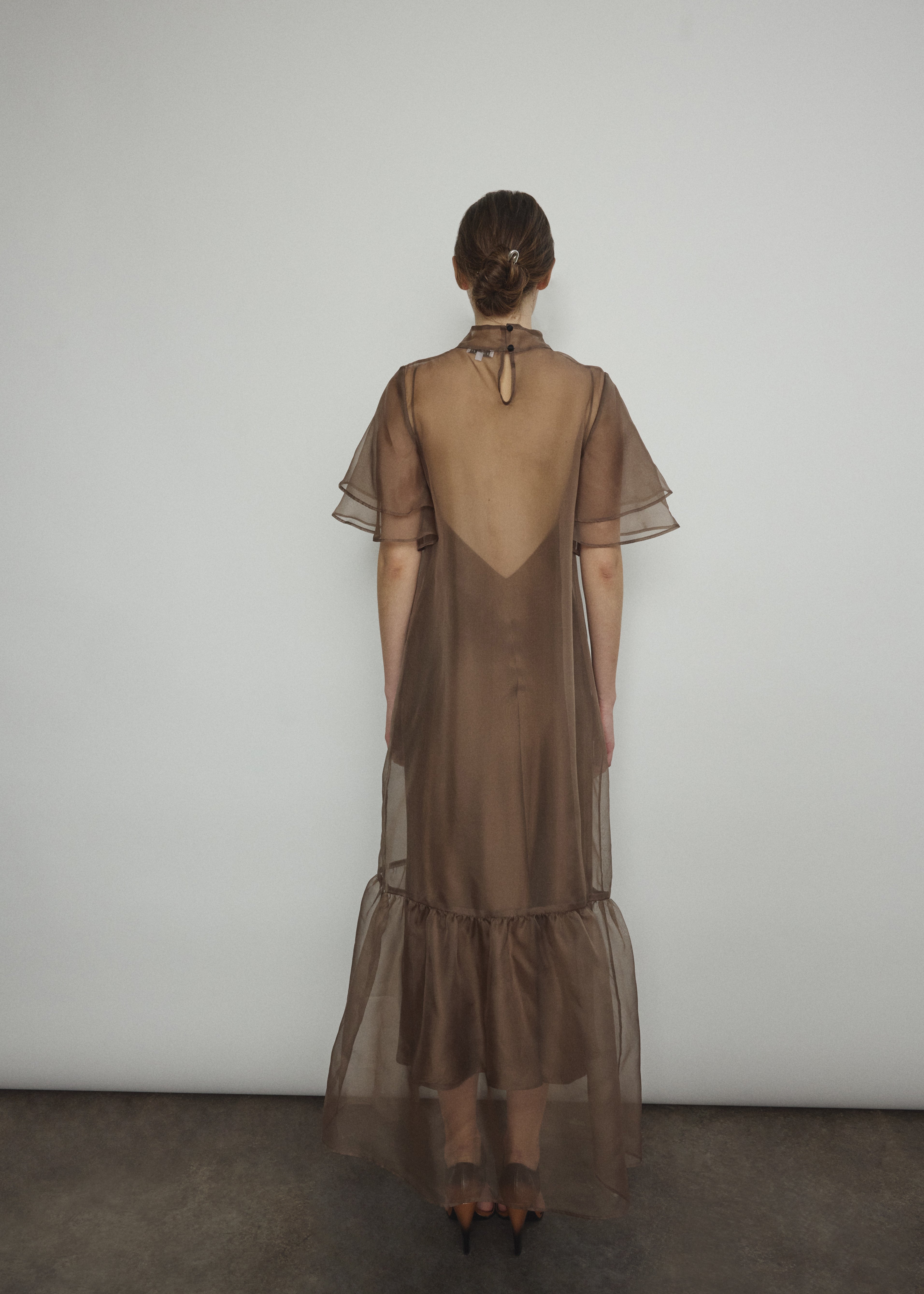 Model in a voluminous mushroom silk organza Barre maxi dress with oversized ruffles and tiered sleeves.