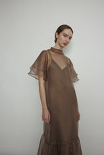 Model in a voluminous mushroom silk organza Barre maxi dress with oversized ruffles and tiered sleeves.