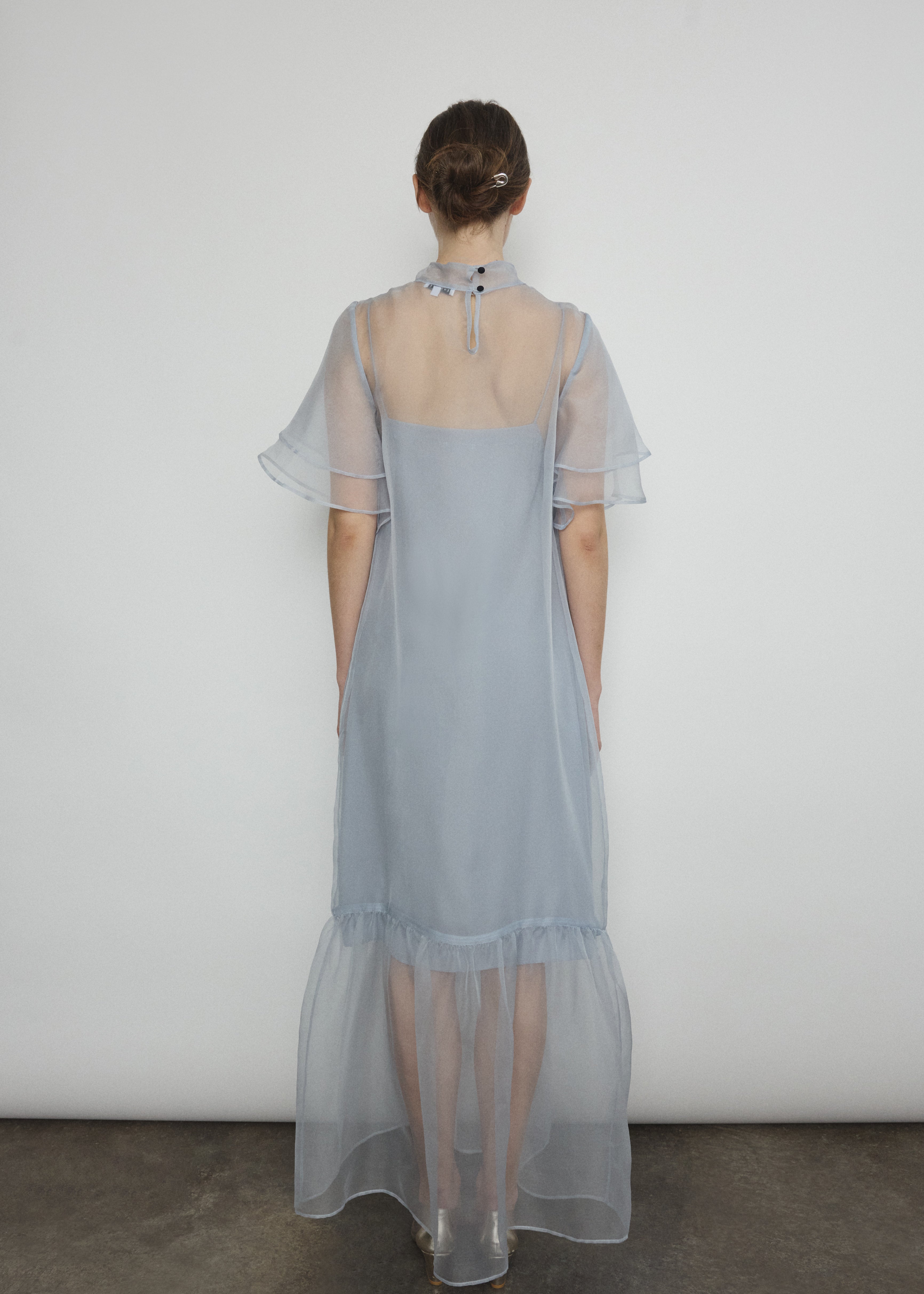 Model in a voluminous blue silk organza Barre maxi dress with oversized ruffles and tiered sleeves.