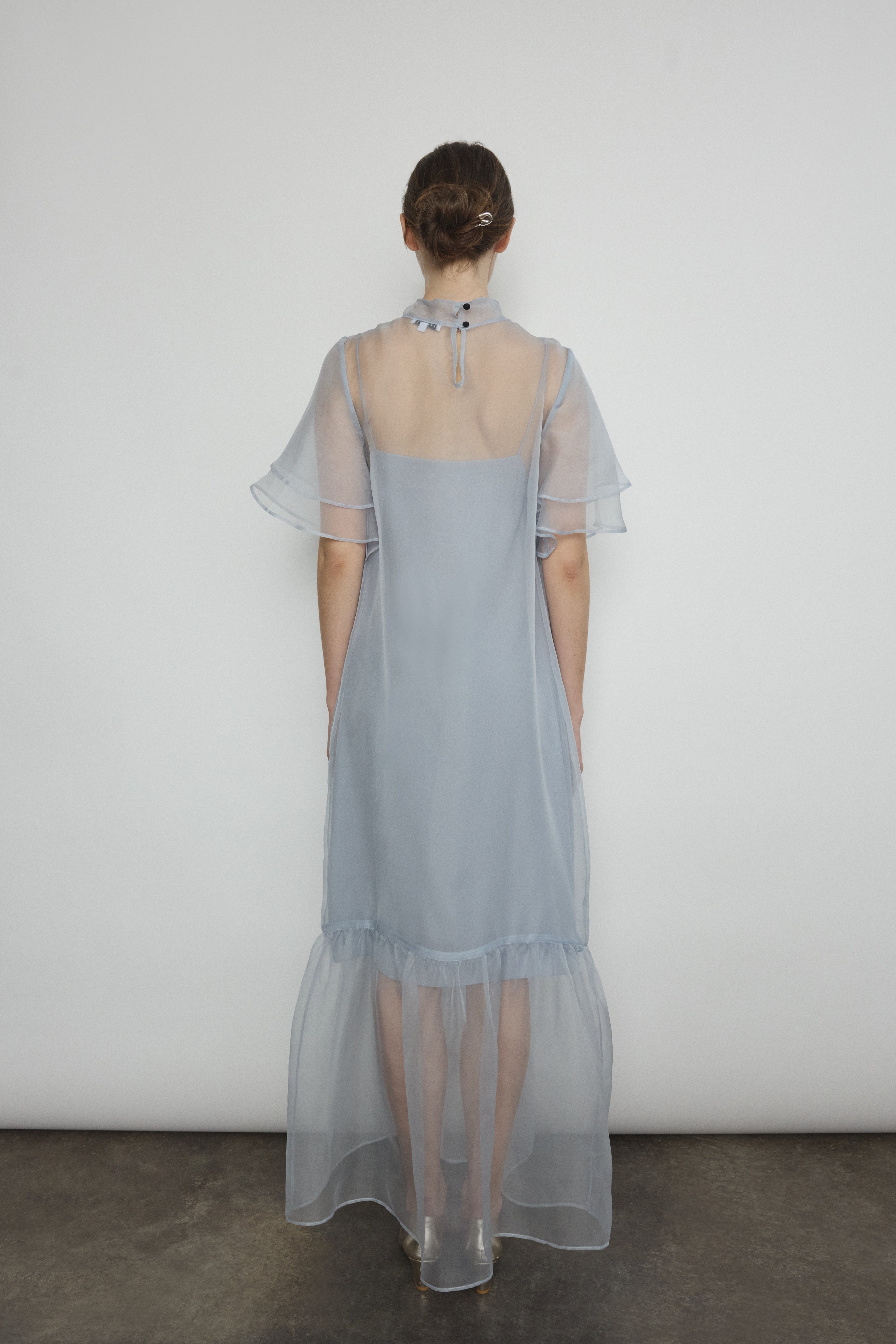 Model in a voluminous blue silk organza Barre maxi dress with oversized ruffles and tiered sleeves.