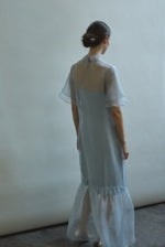 Model in a voluminous blue silk organza Barre maxi dress with oversized ruffles and tiered sleeves.