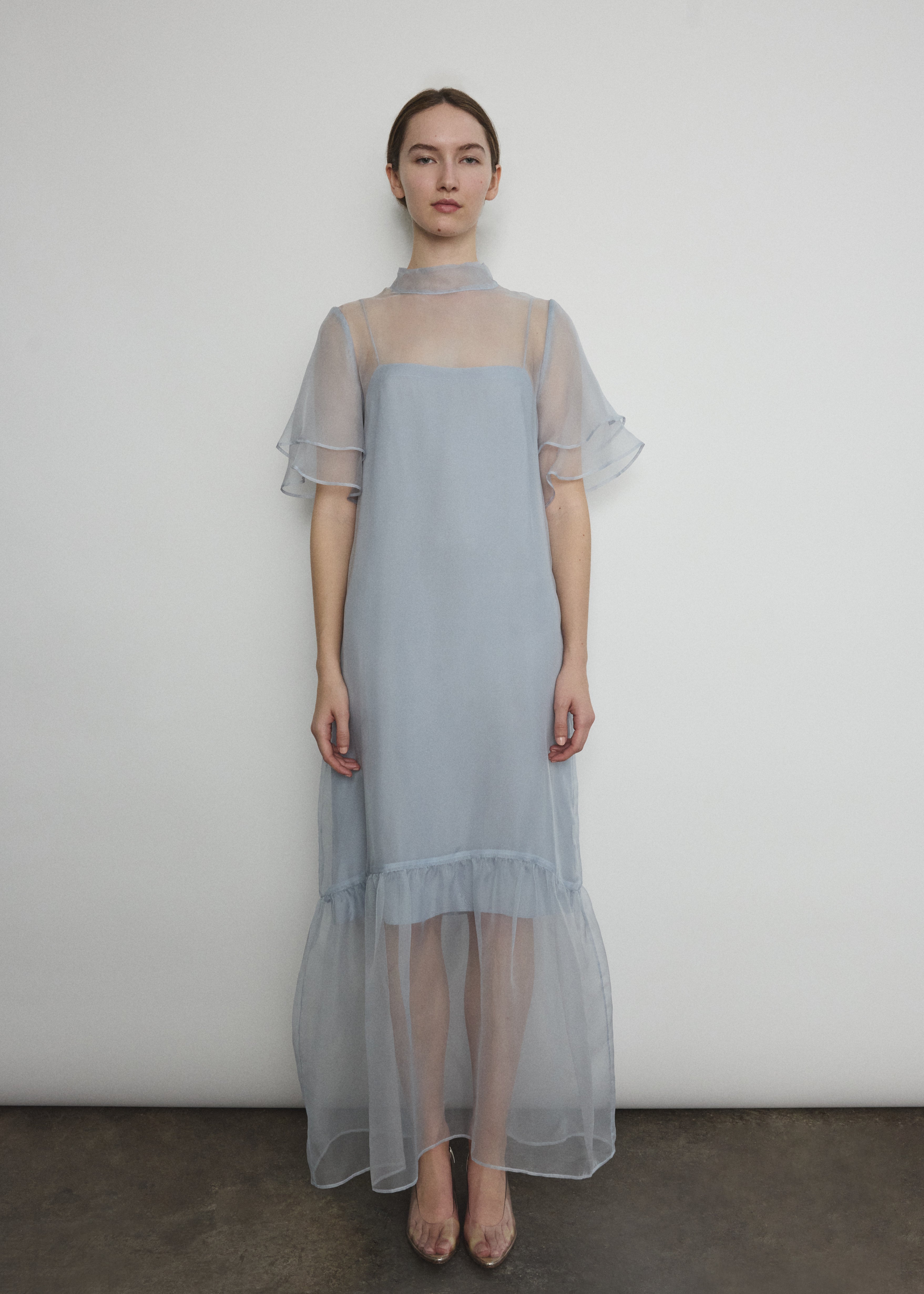 Model in a voluminous blue silk organza Barre maxi dress with oversized ruffles and tiered sleeves.