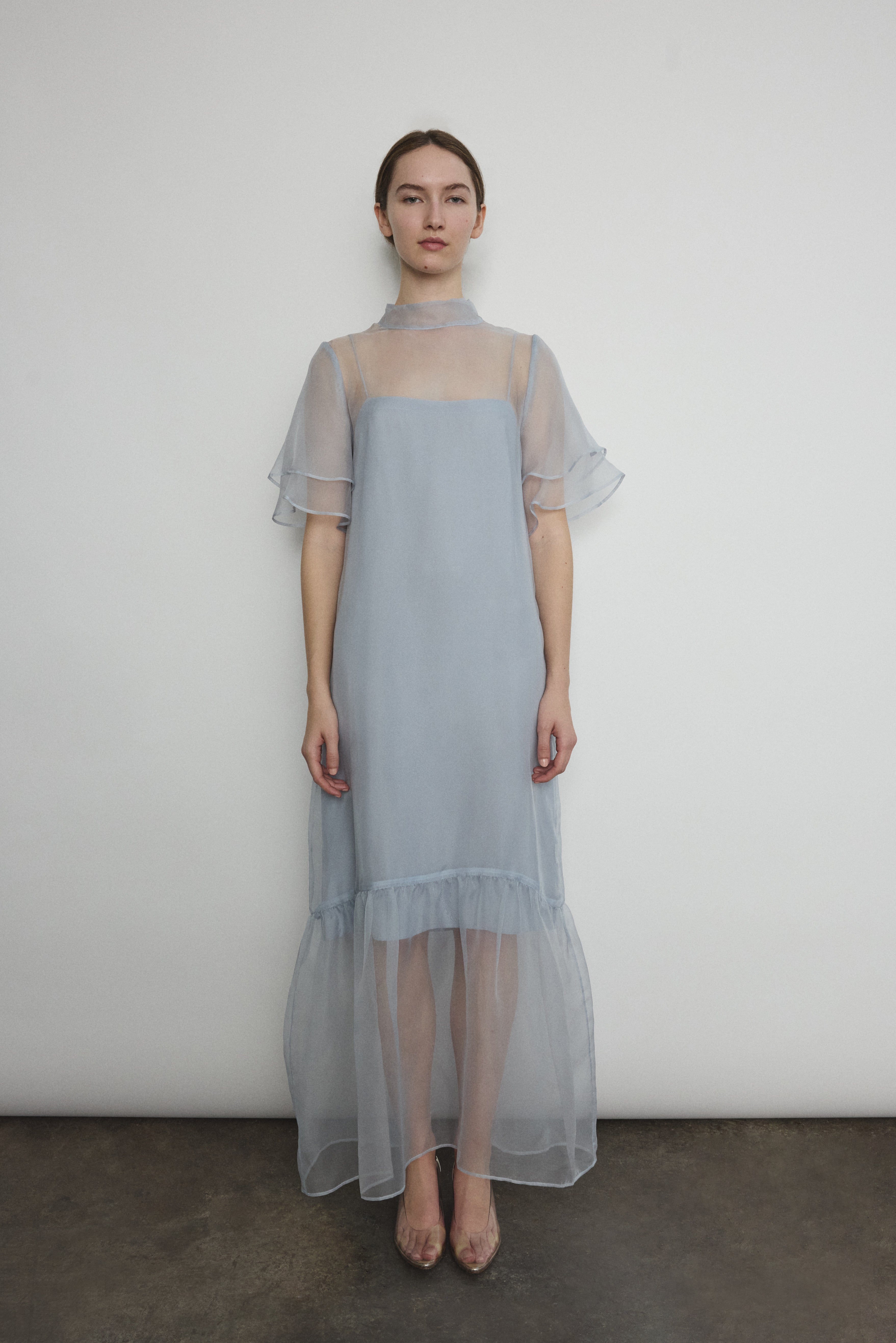 Model in a voluminous blue silk organza Barre maxi dress with oversized ruffles and tiered sleeves.
