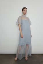 Model in a voluminous blue silk organza Barre maxi dress with oversized ruffles and tiered sleeves.
