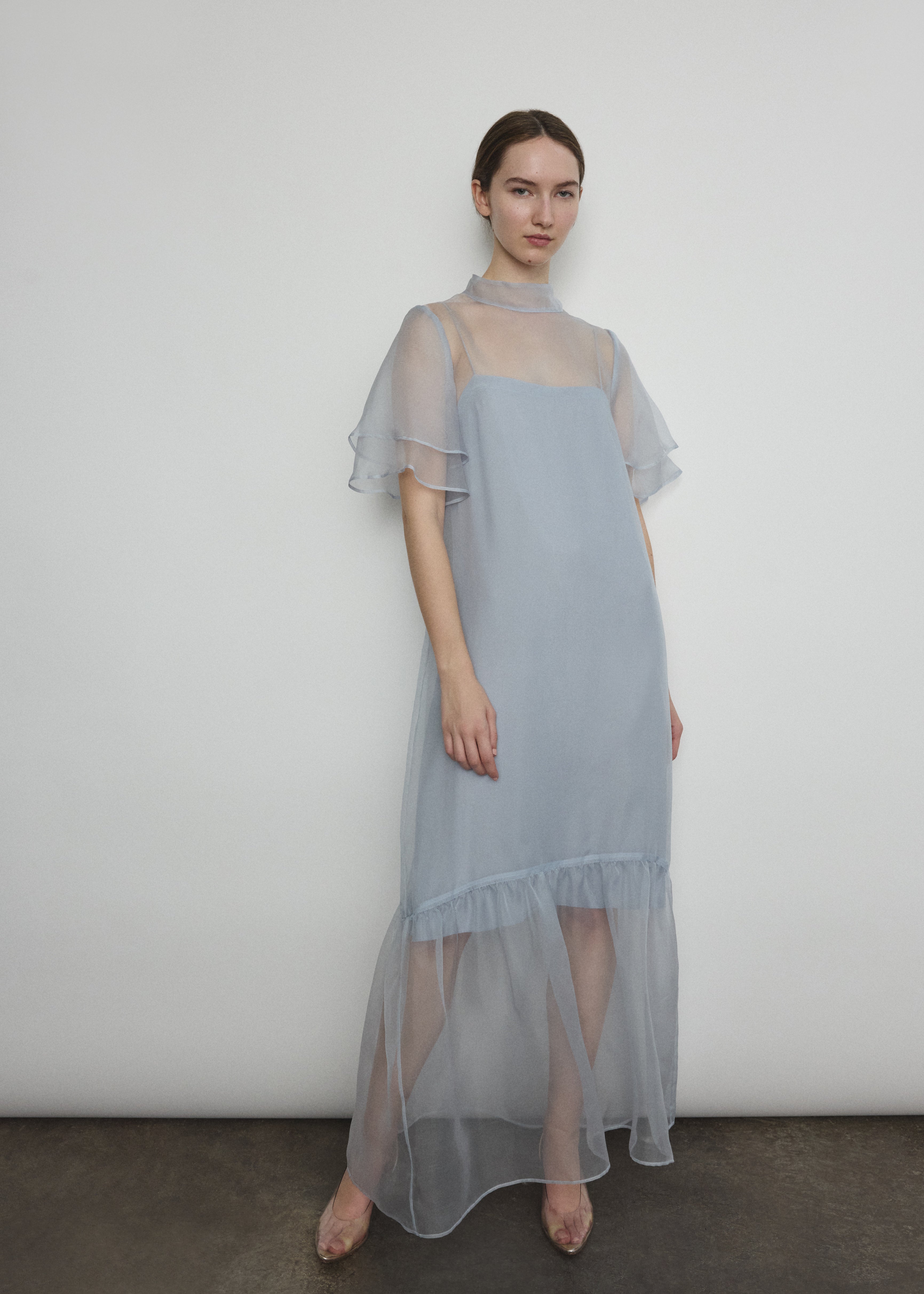 Model in a voluminous blue silk organza Barre maxi dress with oversized ruffles and tiered sleeves.