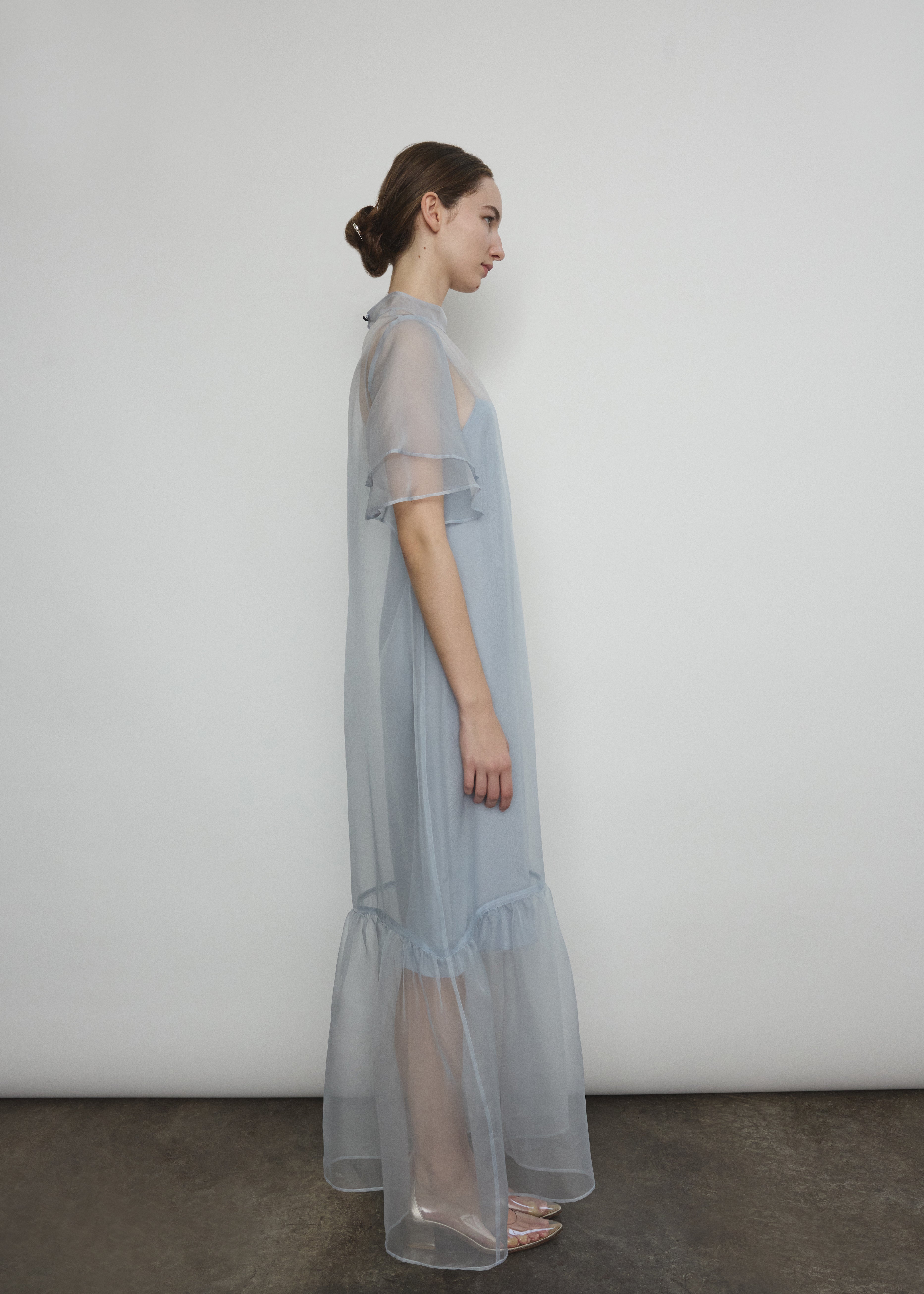 Model in a voluminous blue silk organza Barre maxi dress with oversized ruffles and tiered sleeves.