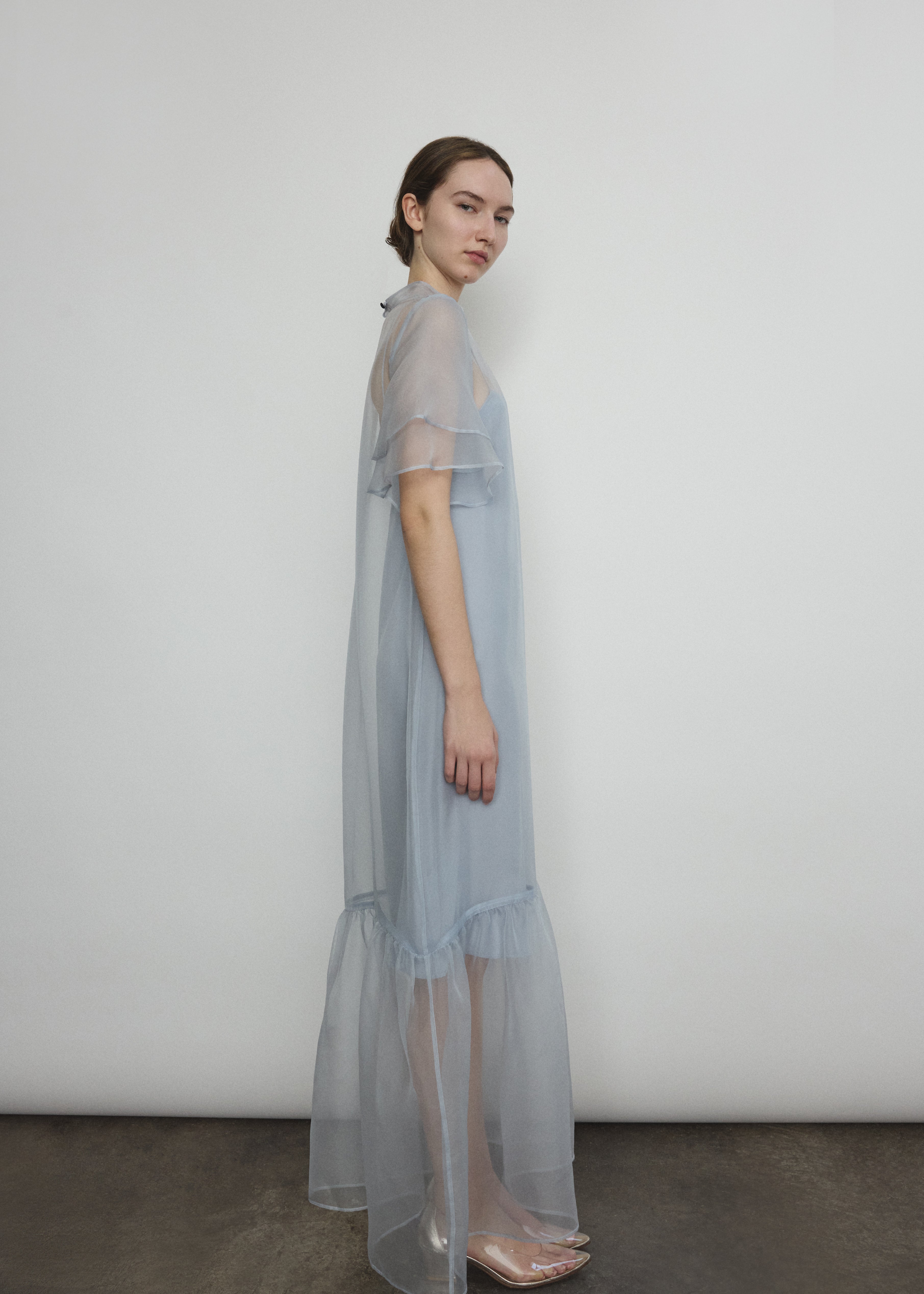Model in a voluminous blue silk organza Barre maxi dress with oversized ruffles and tiered sleeves.