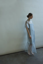 Model in a voluminous blue silk organza Barre maxi dress with oversized ruffles and tiered sleeves.