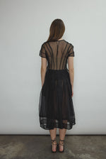 Model wearing the Black silk organza Brise Skirt, showcasing its voluminous silhouette, sheer fabric, and elegant midi-length drape.