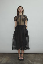 Model wearing the Black silk organza Brise Skirt, showcasing its voluminous silhouette, sheer fabric, and elegant midi-length drape.