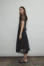 Model wearing the Black silk organza Brise Skirt, showcasing its voluminous silhouette, sheer fabric, and elegant midi-length drape.