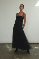 Motion shot of the black sheer tulle Kamperett Camille Dress, capturing the movement of the godet-pleated skirt.