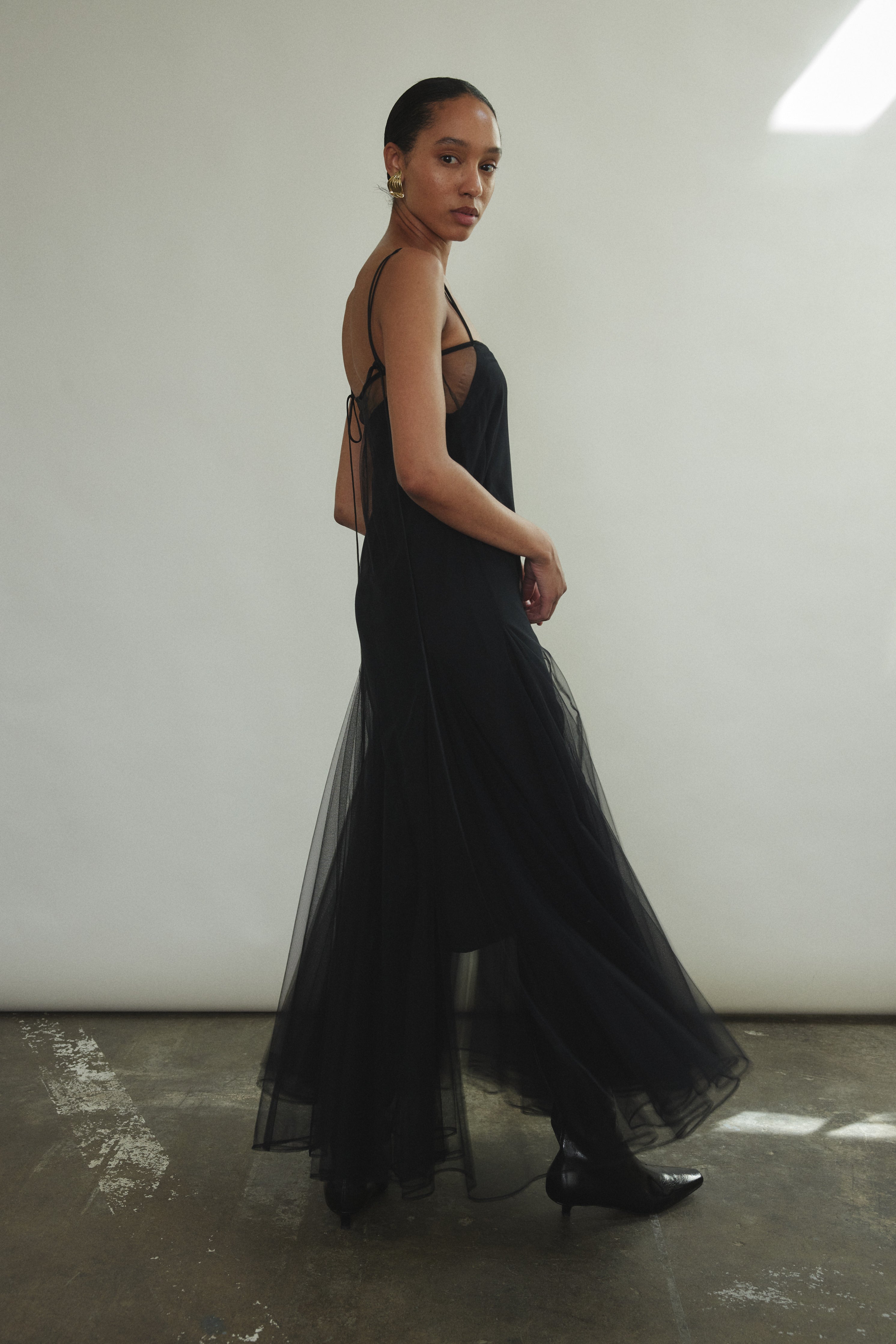 Side motion shot of the black sheer tulle Kamperett Camille Dress, showing the godet skirt in movement.