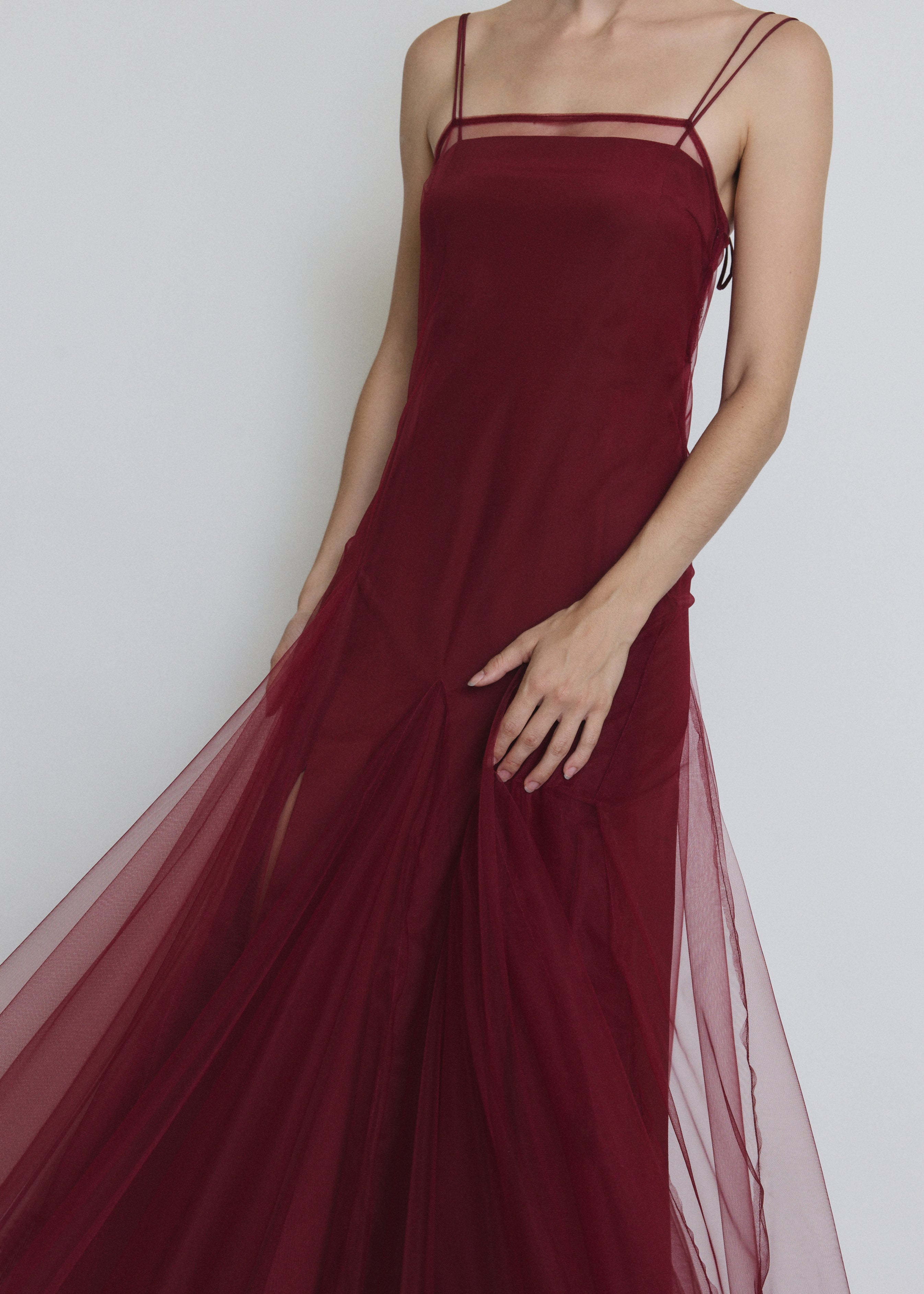 Detail of the bordeaux sheer tulle Kamperett Camille Dress showing the multi-godet hem panelling.