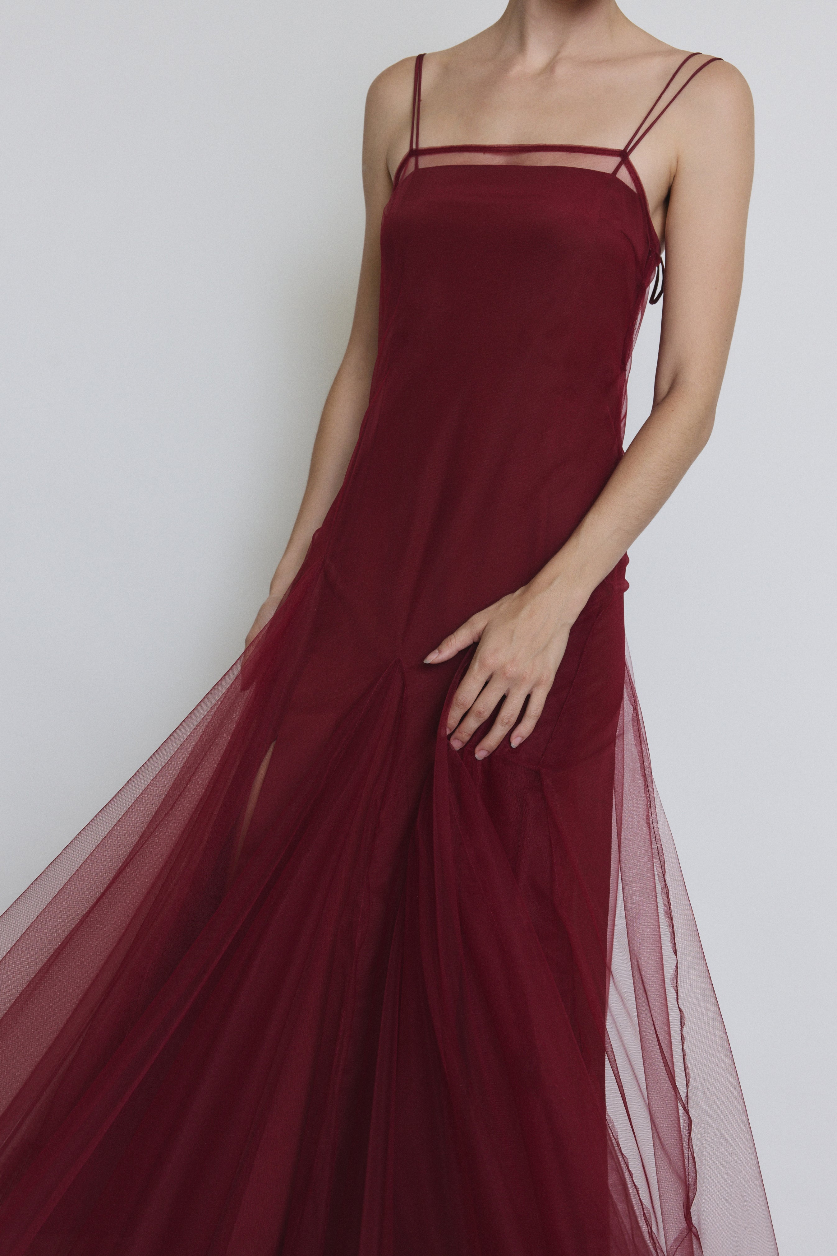 Detail of the bordeaux sheer tulle Kamperett Camille Dress showing the multi-godet hem panelling.