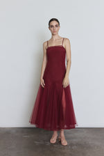 Front view of a model wearing the bordeaux sheer tulle Kamperett Camille Dress, a tea-length overlay with straight neckline and spaghetti straps.
