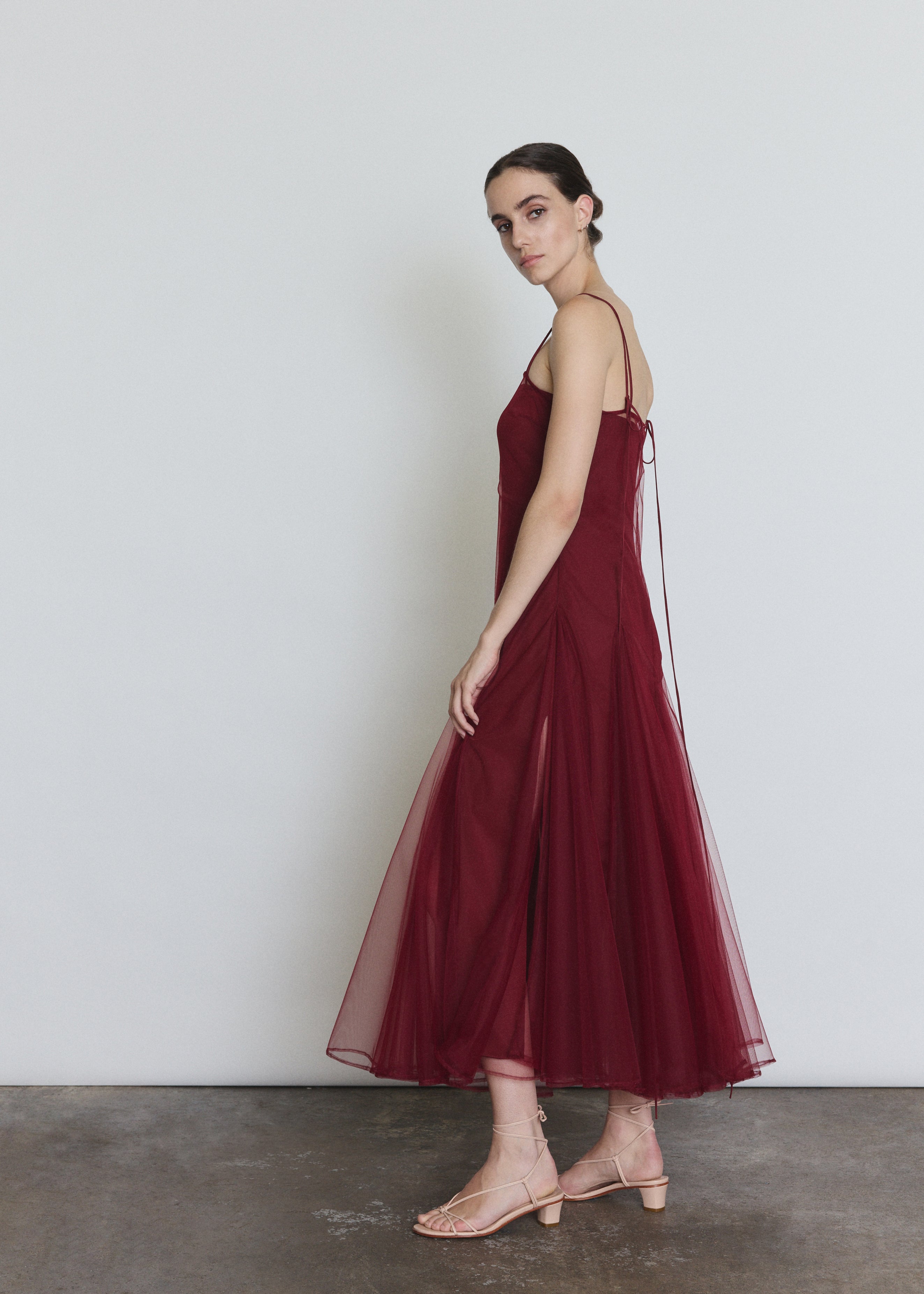 Side view of the bordeaux sheer tulle Kamperett Camille Dress showing the multi-godet full skirt.