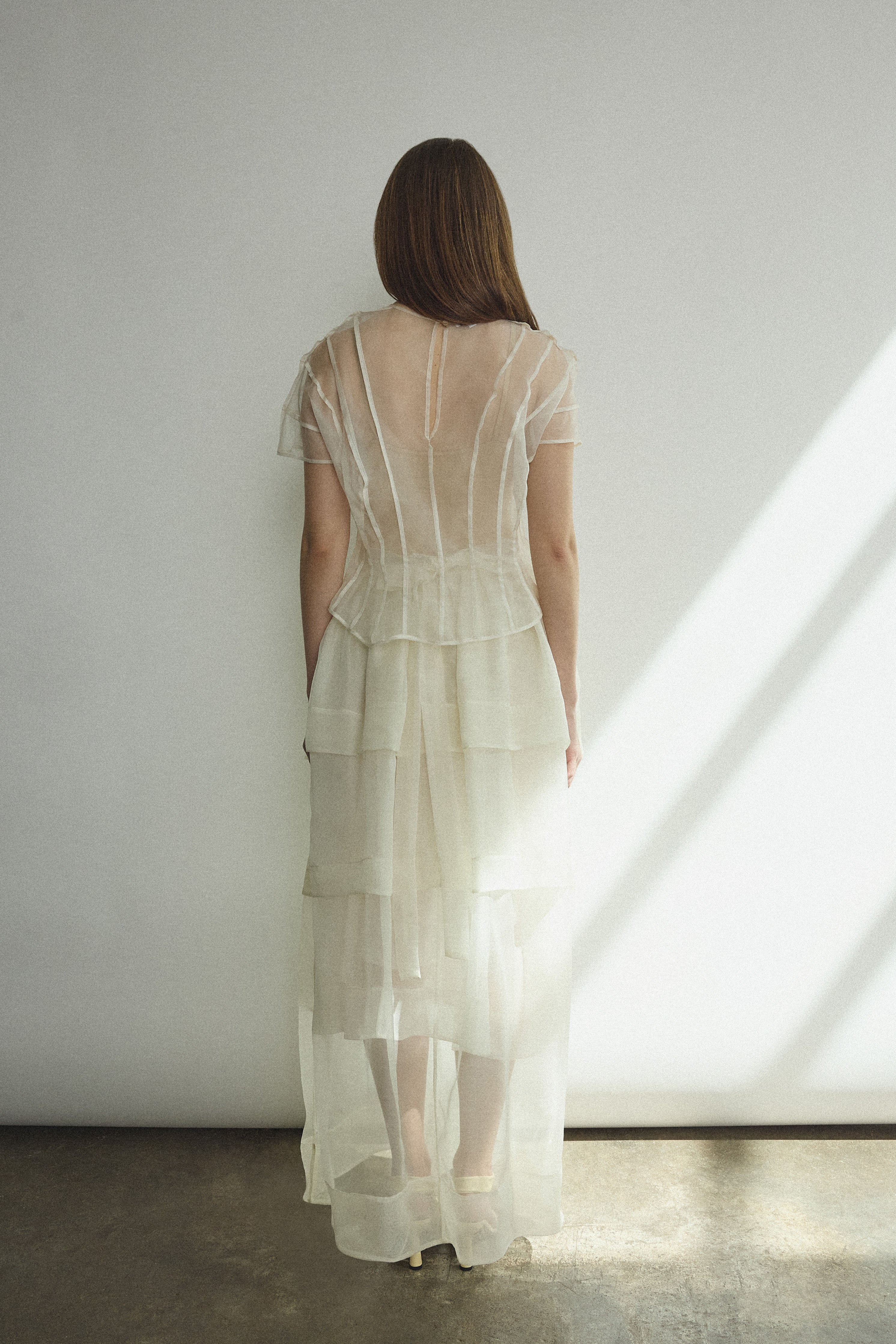 Back view of the alabaster Kamperett Canna Skirt layered over the Brise Skirt with waist ties tied at back.