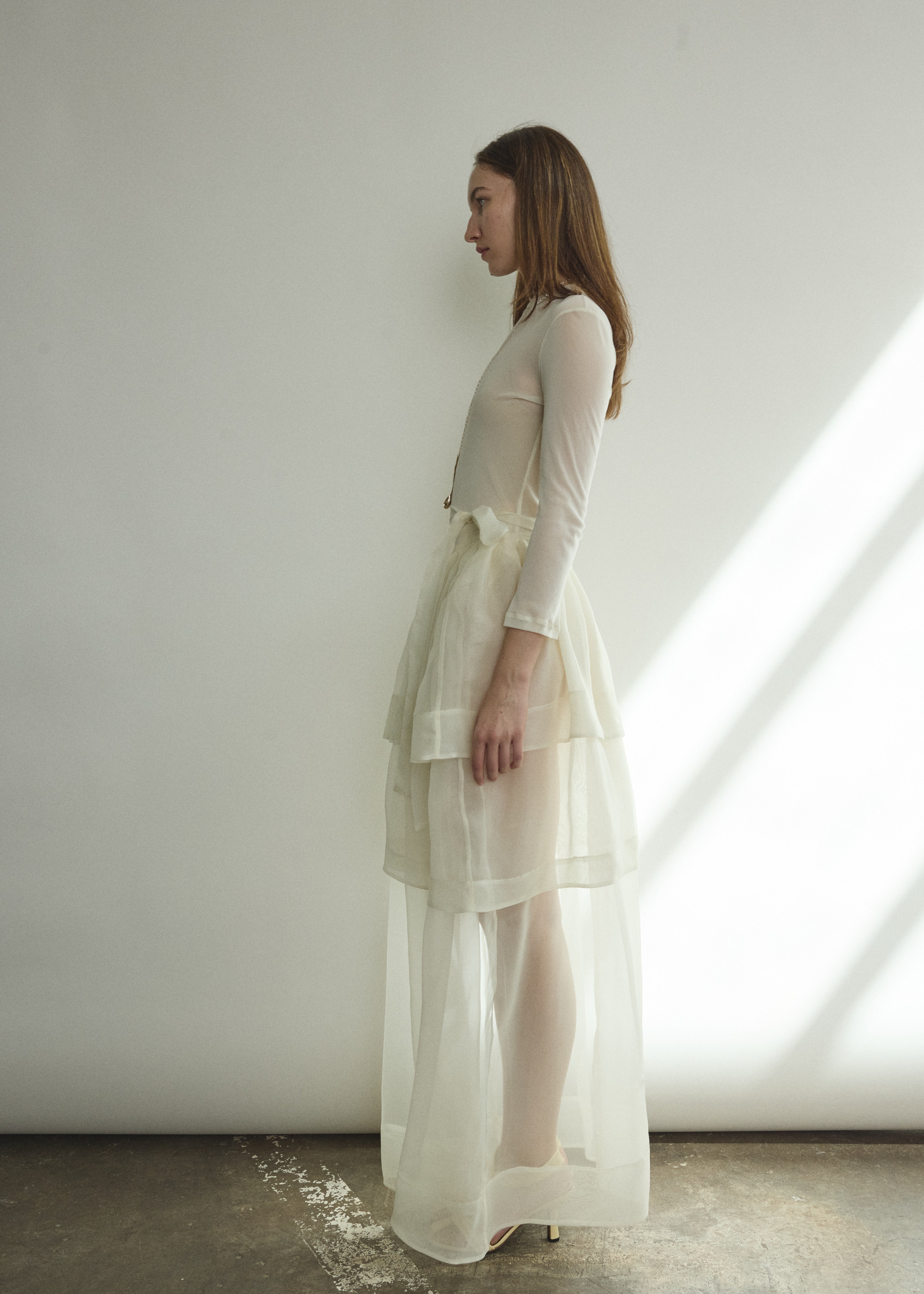 Motion shot of the alabaster sheer silk organza Kamperett Canna Skirt, capturing the fluid pleated drape.