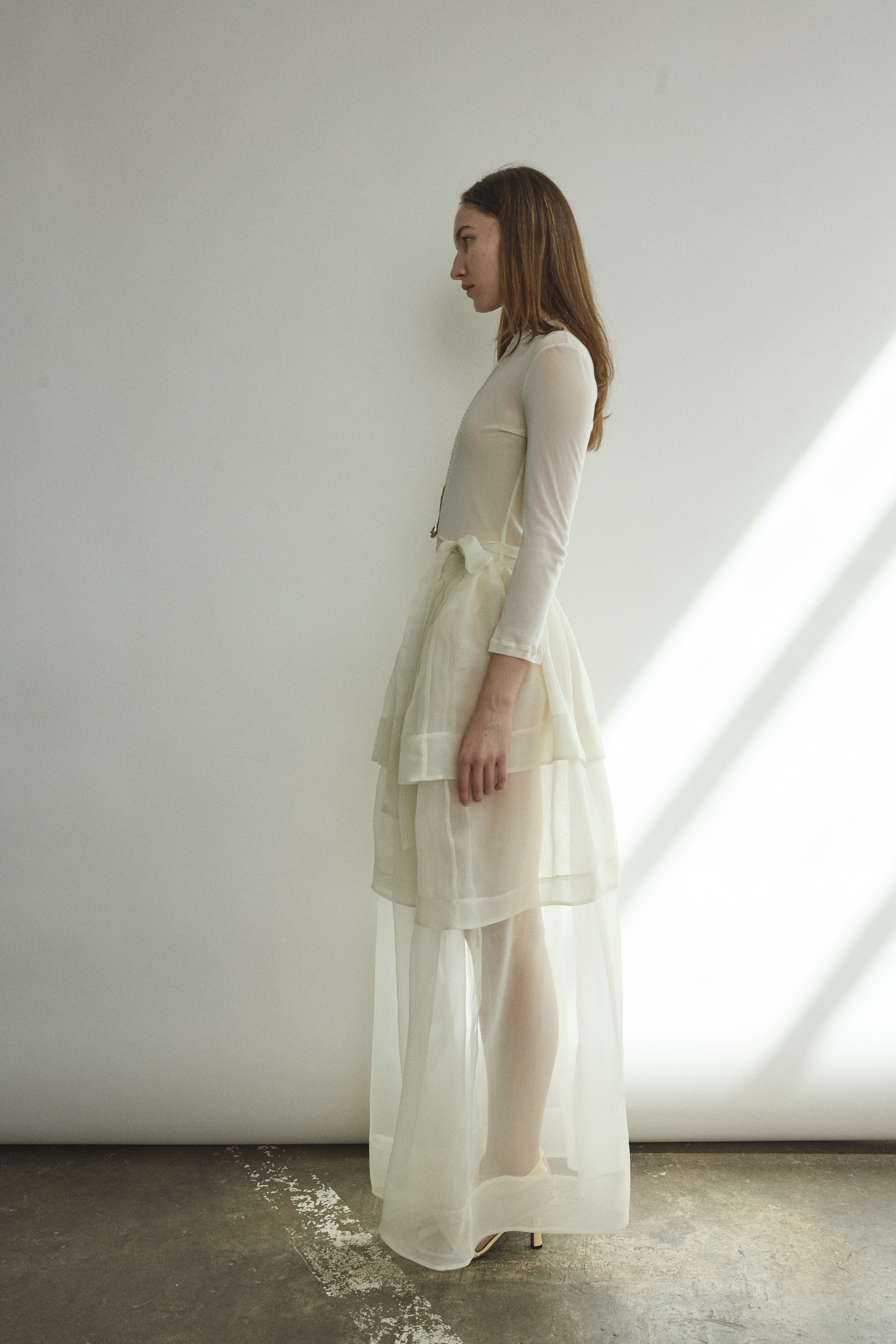 Motion shot of the alabaster sheer silk organza Kamperett Canna Skirt, capturing the fluid pleated drape.