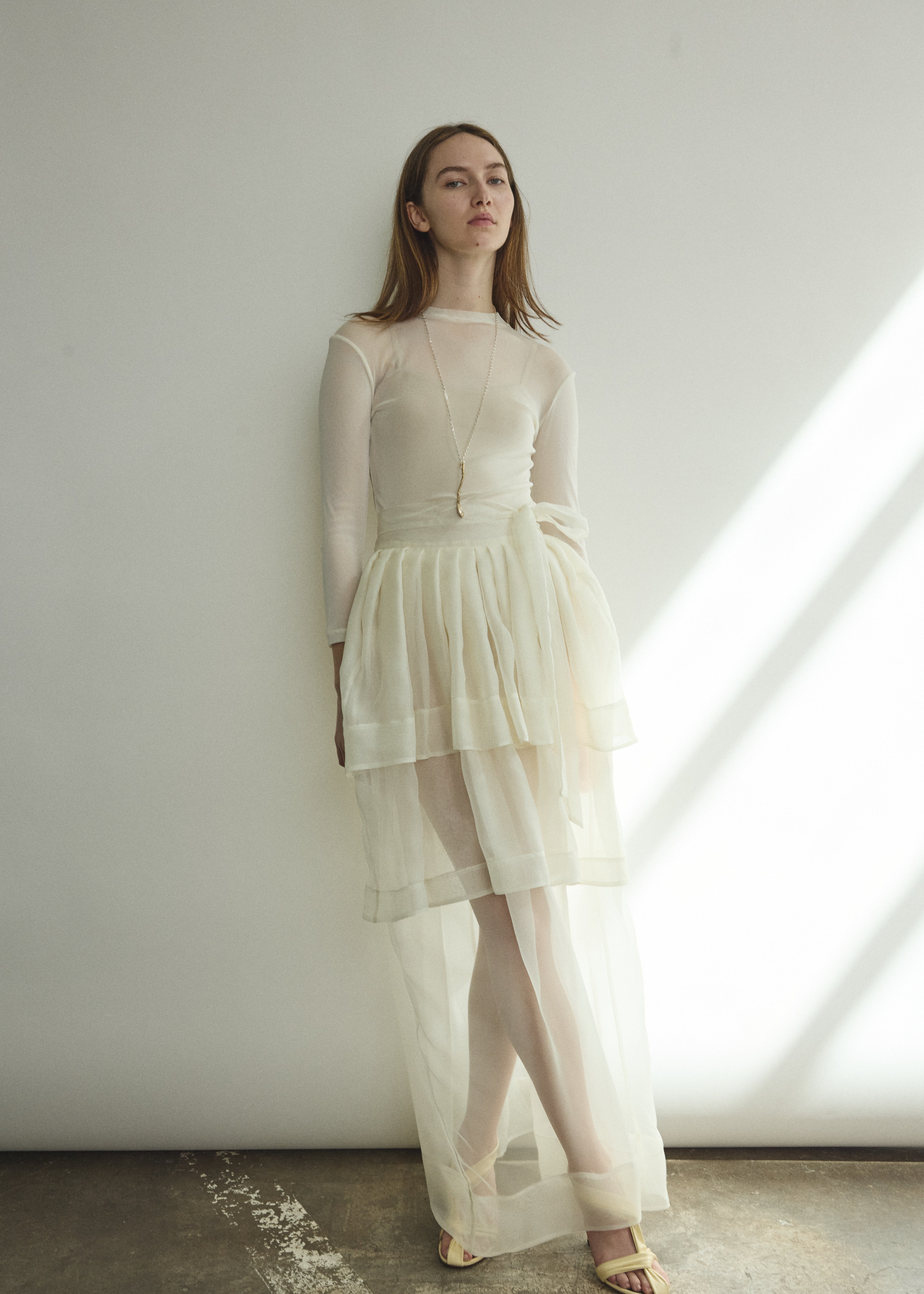 Side view of the alabaster sheer silk organza Kamperett Canna Skirt, showing the pleated multi-tier construction.