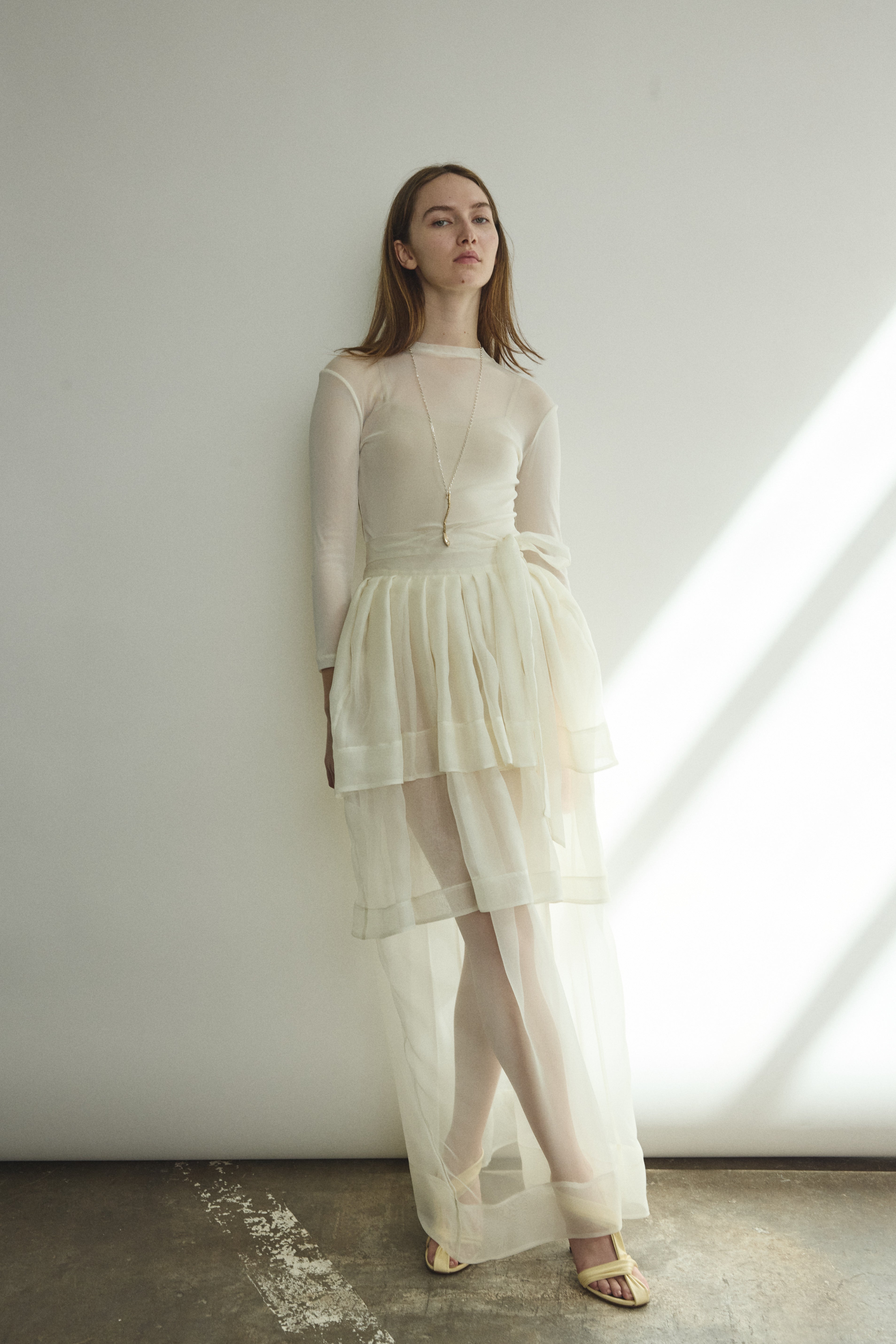 Side view of the alabaster sheer silk organza Kamperett Canna Skirt, showing the pleated multi-tier construction.
