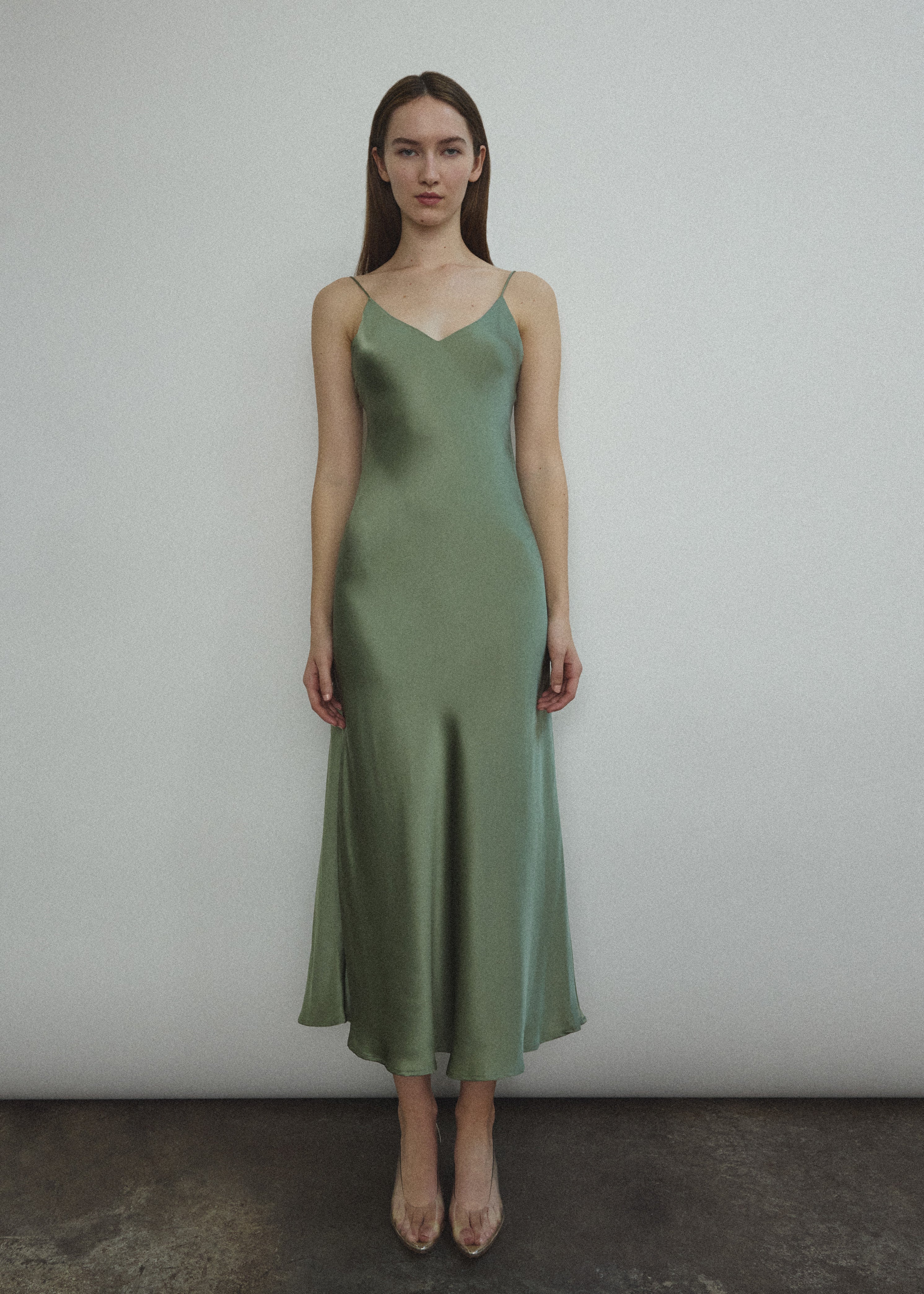 Front view of a model wearing the jade sueded silk charmeuse Kamperett Caroline Midi Slip Dress with V-neckline and corded straps.