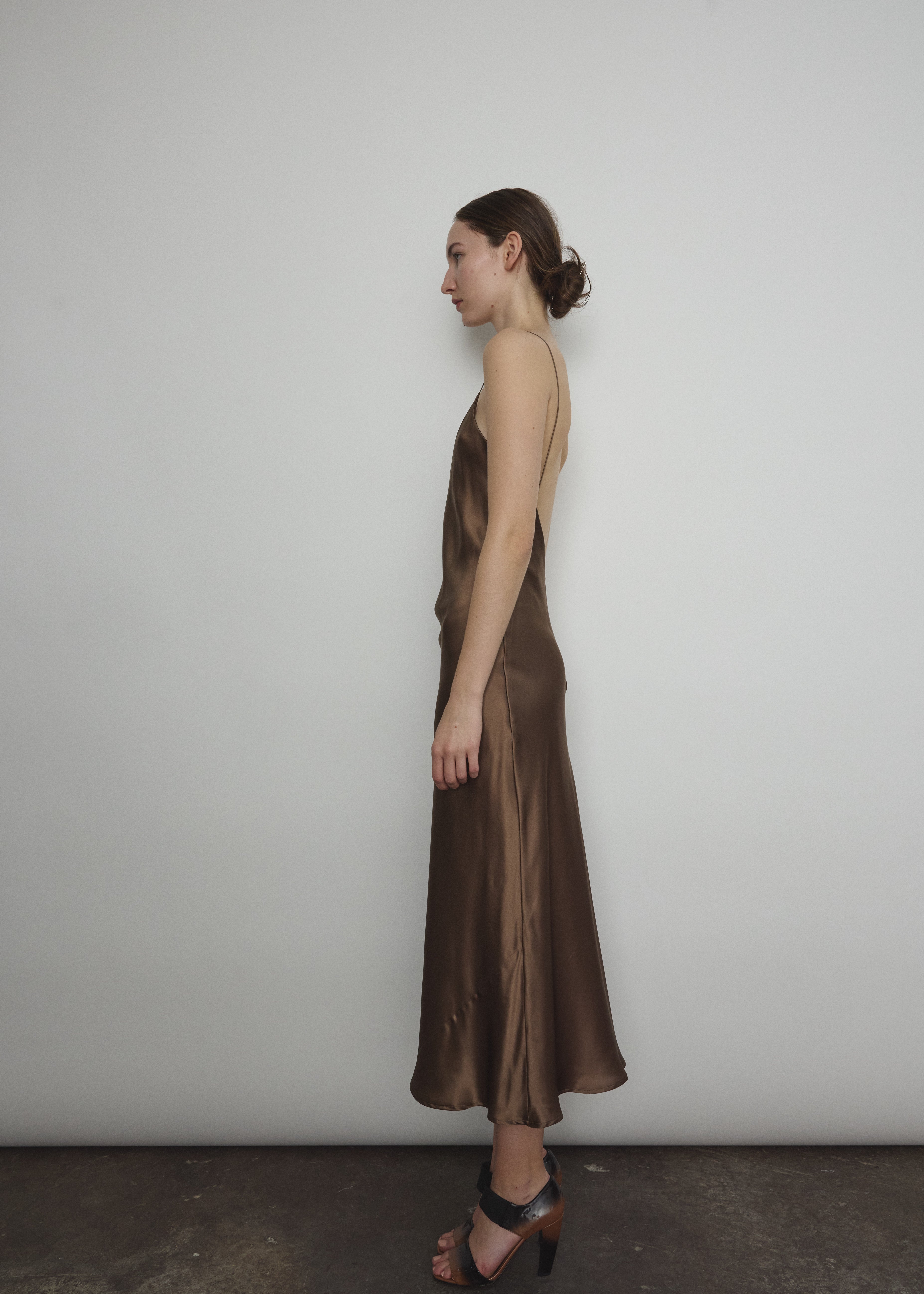 Side view of the mushroom sueded silk charmeuse Kamperett Caroline Midi Slip Dress, showing the bias-cut drape.