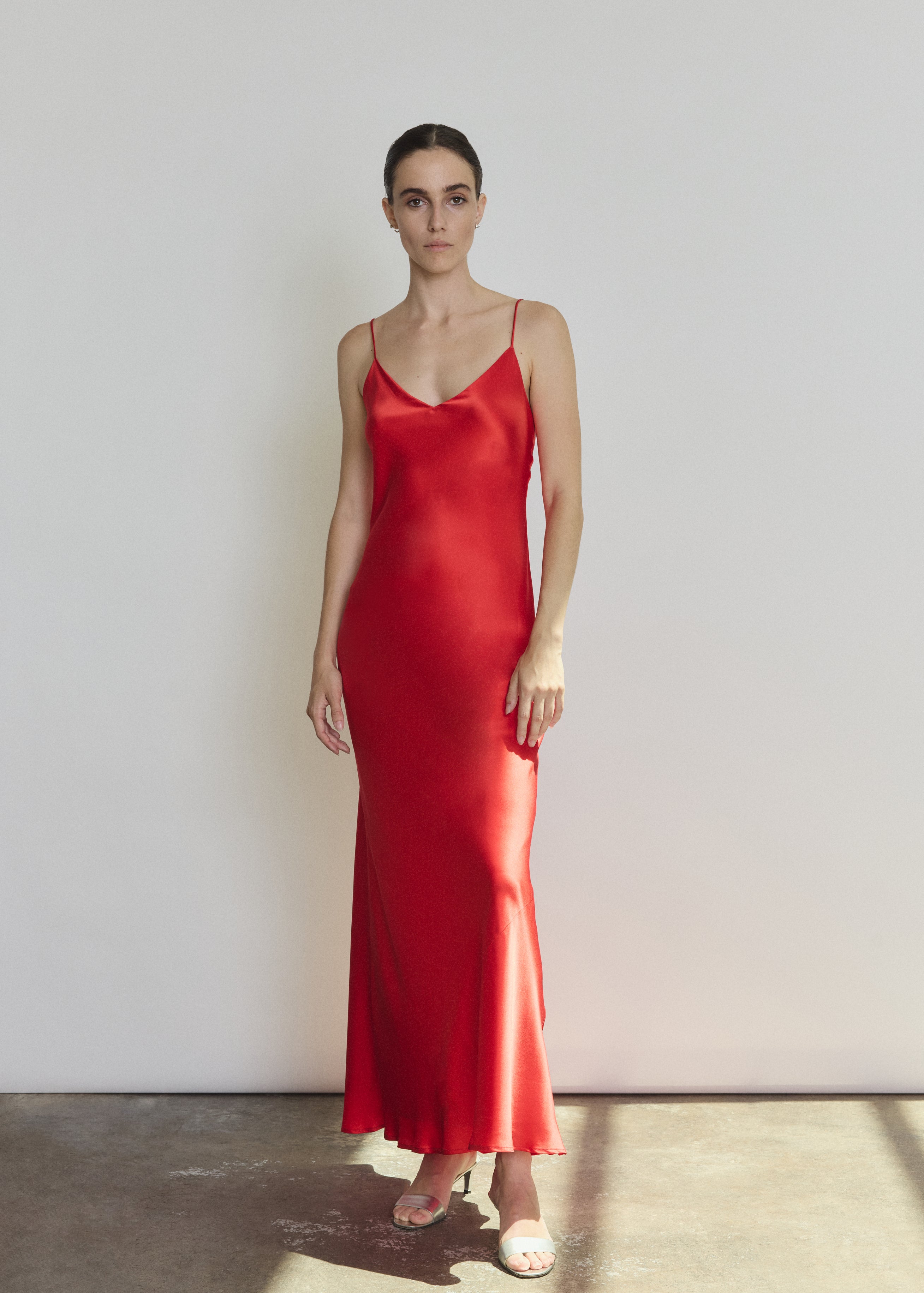 Front view of a model wearing the crimson silk charmeuse Kamperett Caroline Slip Dress, a bias-cut maxi slip with V neck and corded straps.