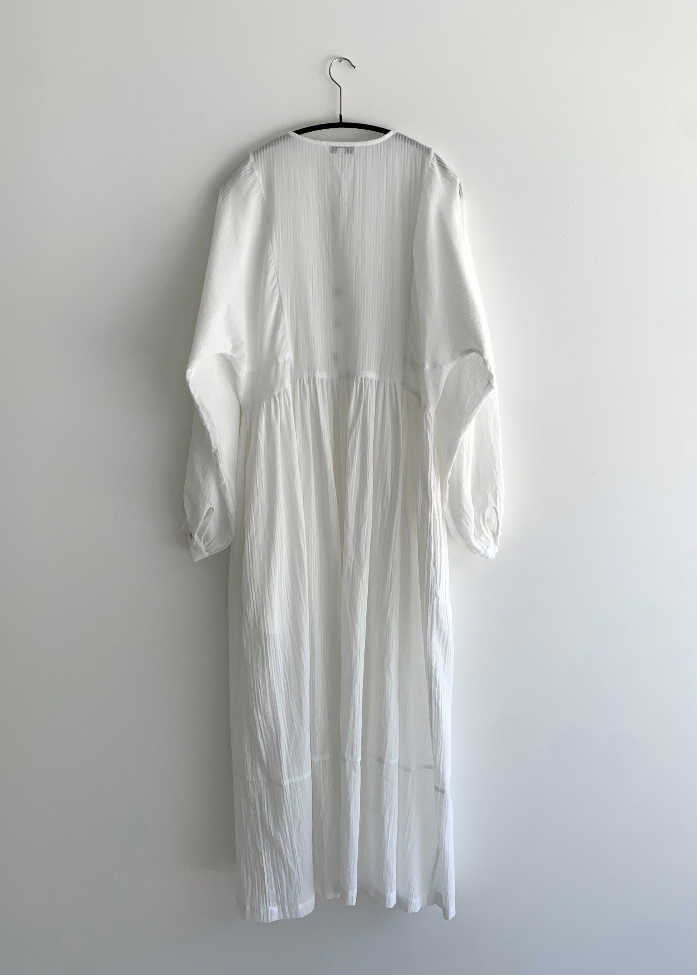Close-up of the dolman sleeve and button cuff on the semi-sheer white stripe Kamperett Cassatt Dress.