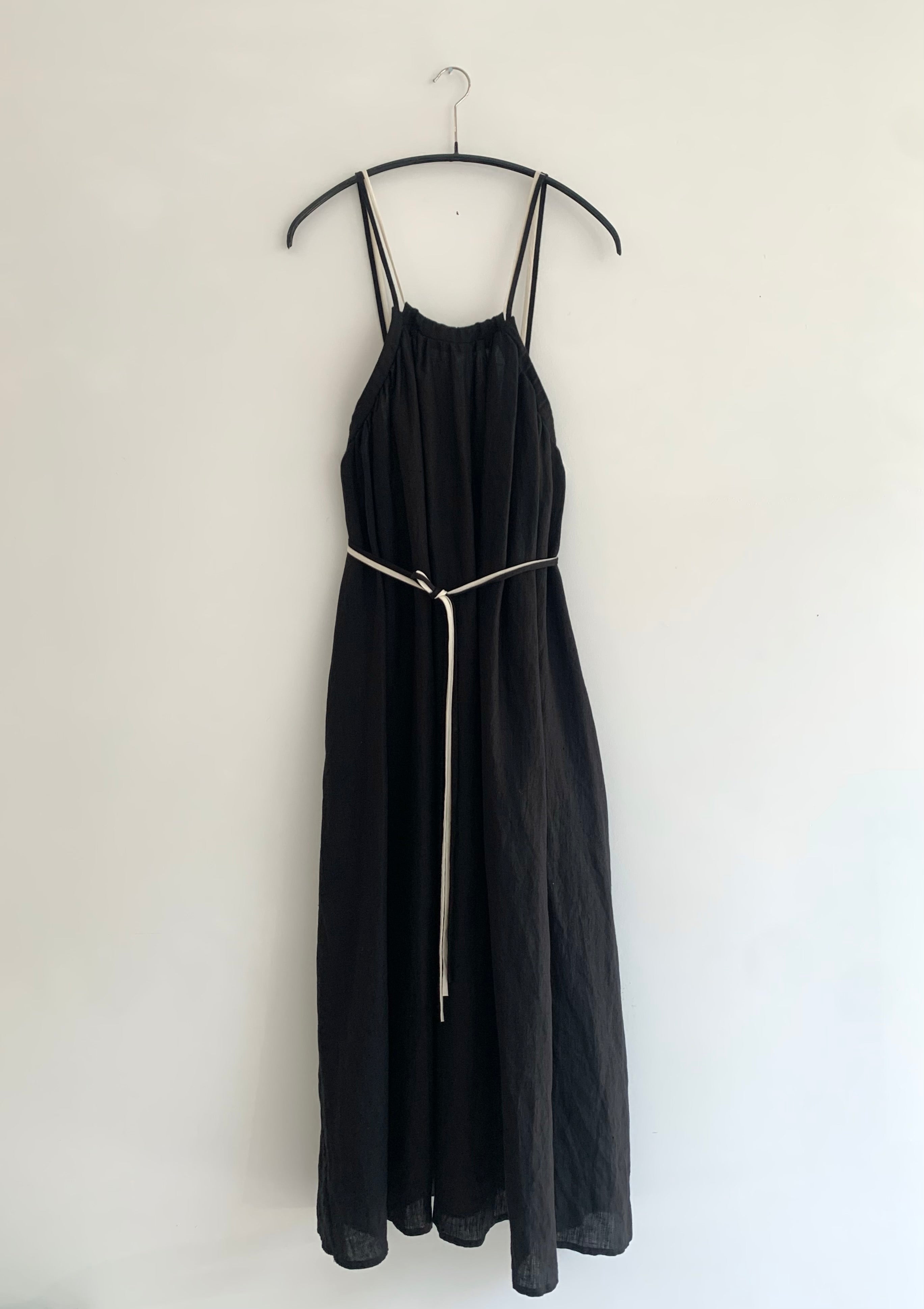 Front view of a model wearing the black Japanese linen Kamperett Cosette Dress with gathered neckline and trapeze silhouette.