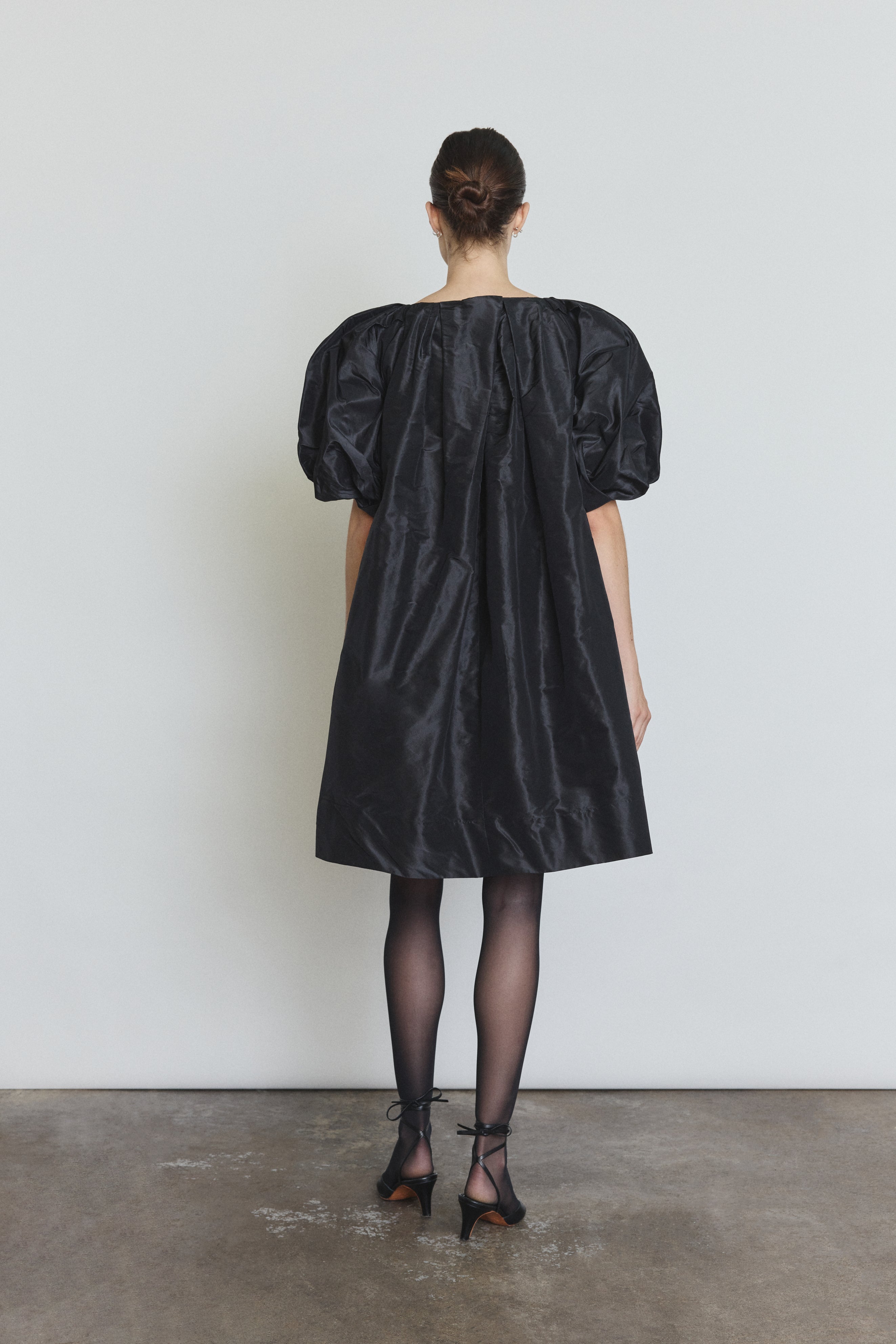 Detail of the black silk taffeta Kamperett Eva Dress showing the asymmetrical pleat construction at the neckline.