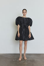Editorial image of a model wearing the black Kamperett Eva Dress, a modern sculptural silk taffeta mini.