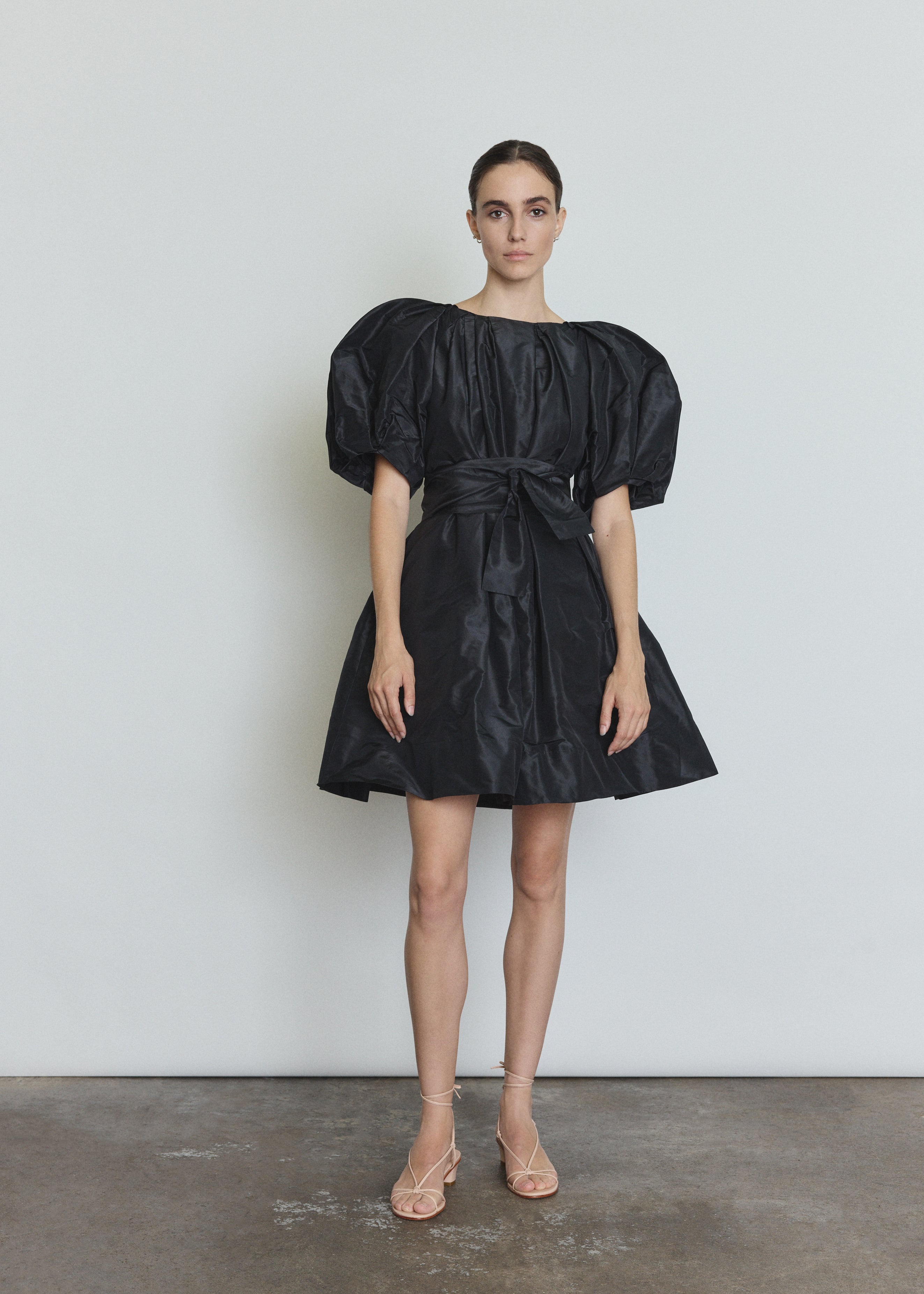 Editorial image of a model wearing the black Kamperett Eva Dress, a modern sculptural silk taffeta mini.