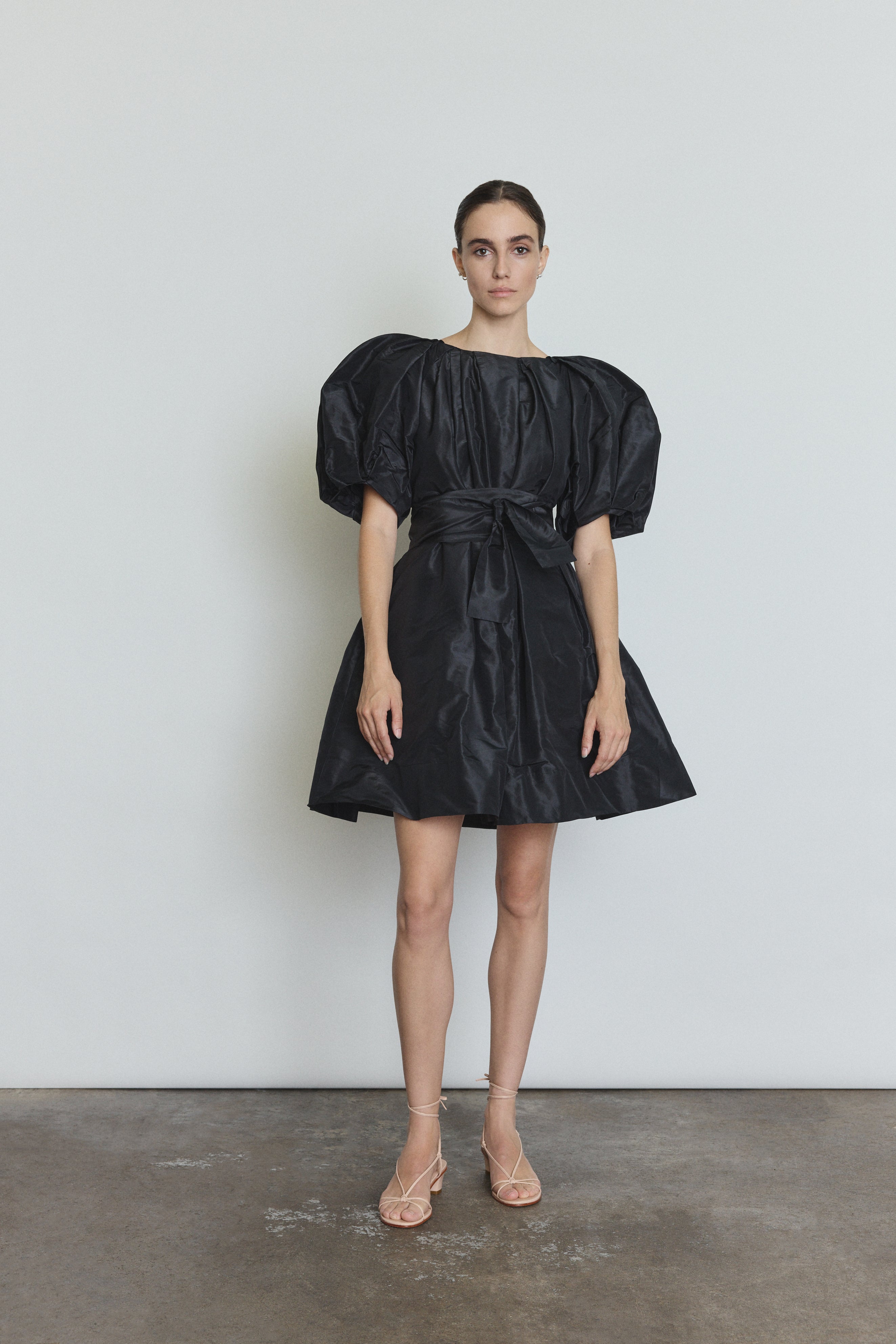 Editorial image of a model wearing the black Kamperett Eva Dress, a modern sculptural silk taffeta mini.