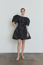Editorial image of the black Kamperett Eva Dress cinched at the waist with the coordinating silk taffeta belt.