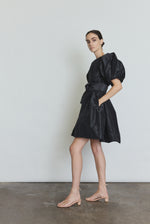 Editorial image of the black Kamperett Eva Dress showing the full A-line silhouette from behind.