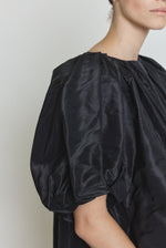 Editorial image of the black Kamperett Eva Dress showing the sculptural pleat construction.