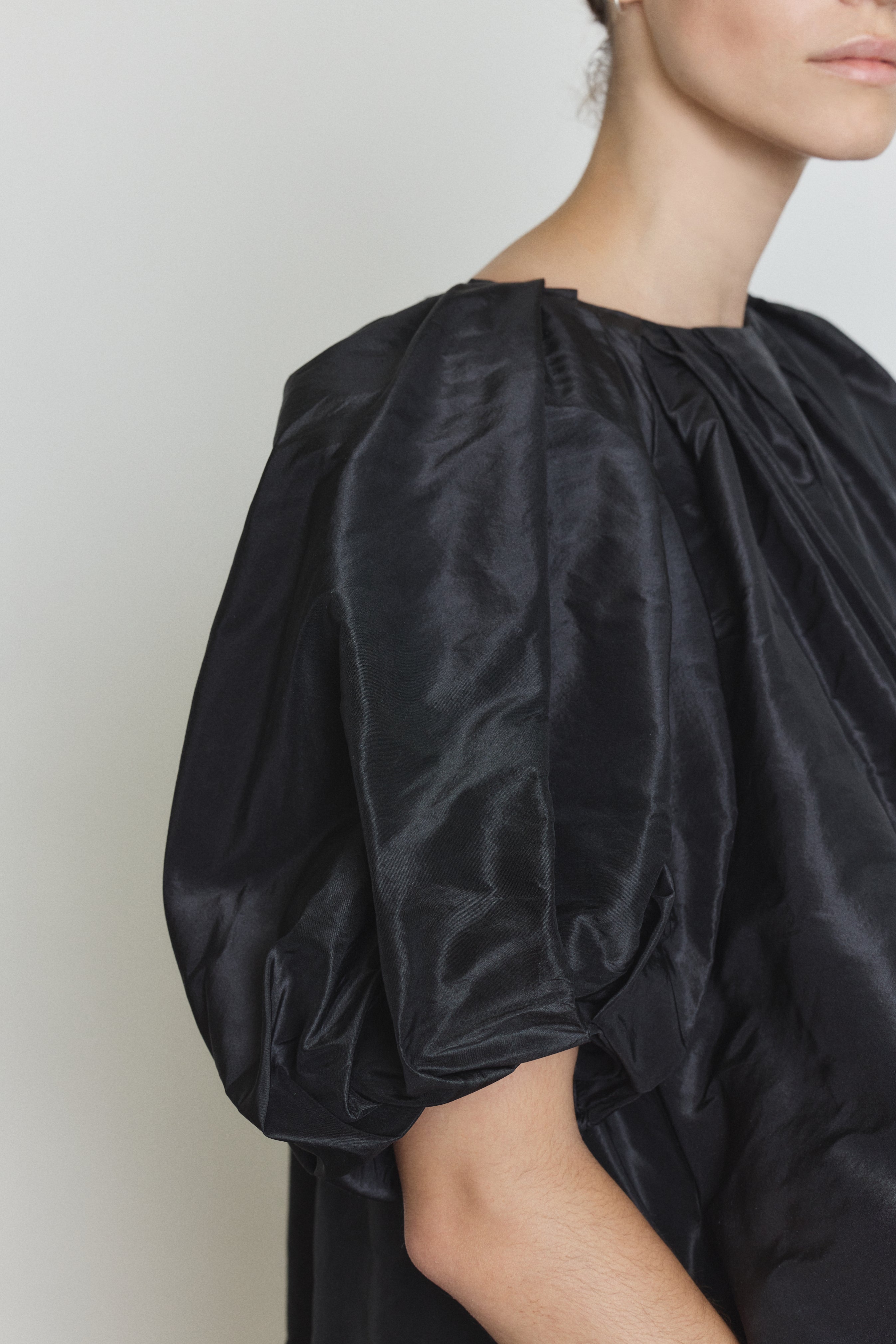 Editorial image of the black Kamperett Eva Dress showing the sculptural pleat construction.