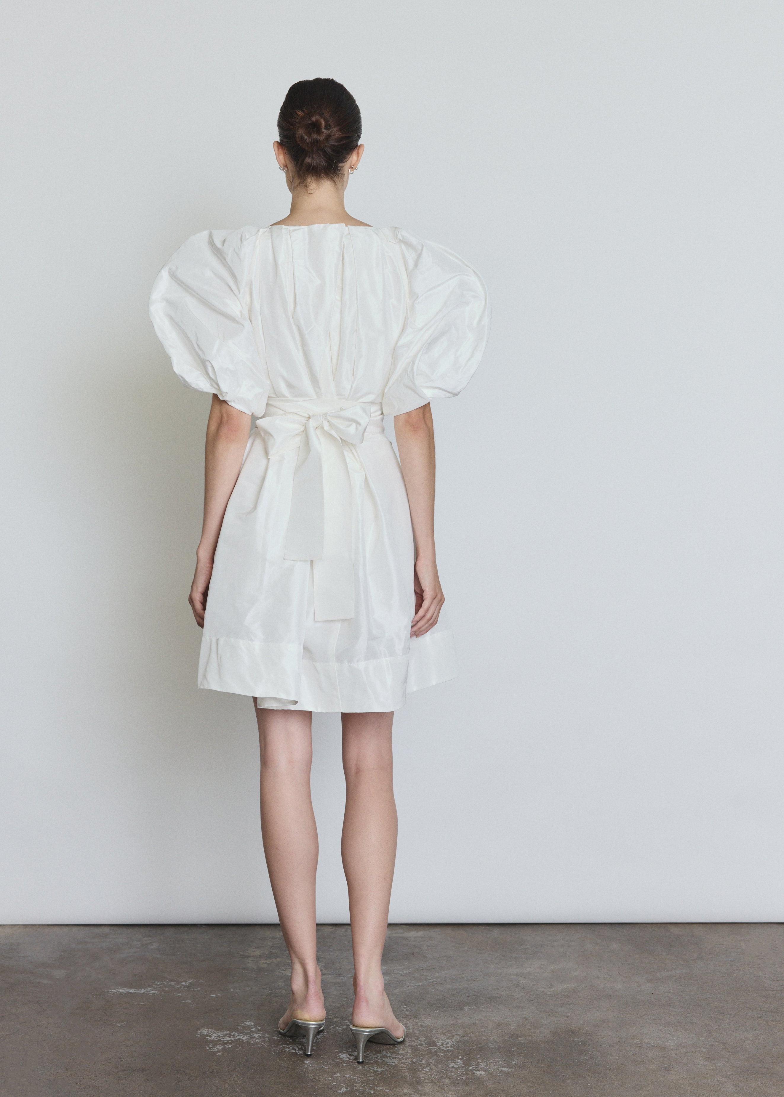 Editorial image of a bride wearing the white Kamperett Eva Dress, a modern sculptural silk taffeta bridal mini.